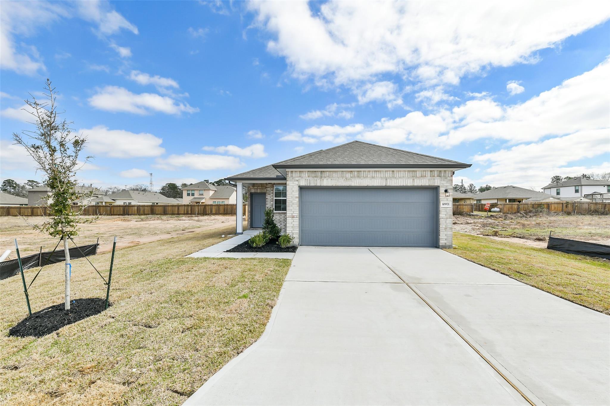 Modern 4-bedroom single-story home exterior with 2-car garage, driveway, and front yard landscaping in Liberty Estates, Cleveland, Texas