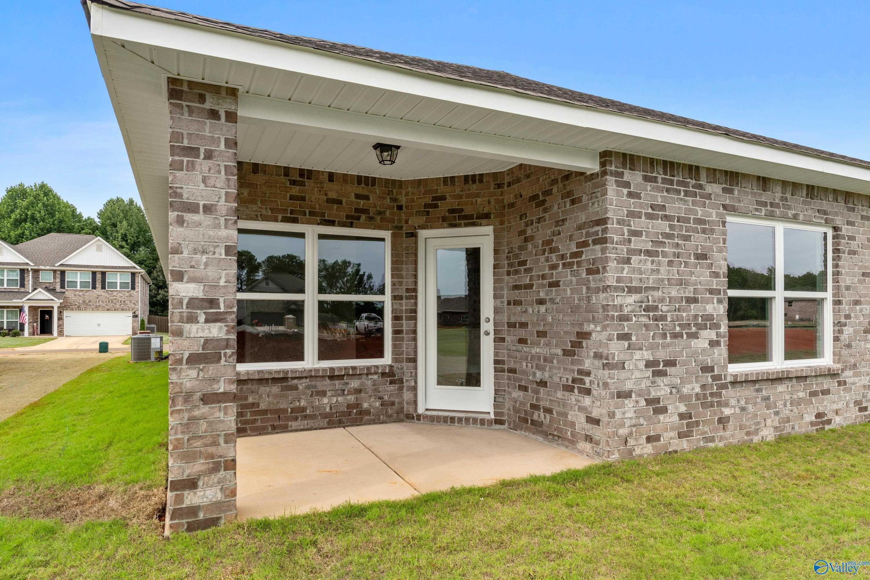 Brick exterior of Davidson Homes The Daphne C with covered front porch, white door, and windows in Ricketts Farm, Athens, Alabama