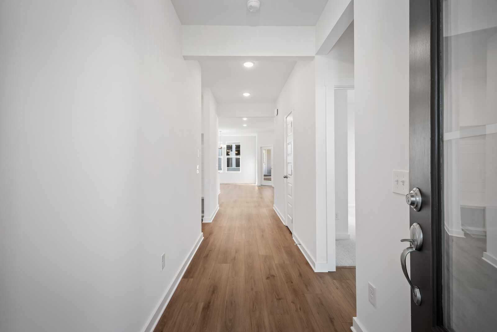 Bright hallway with white walls, light wood floors, recessed lights, and side doors in Davidson Homes The Franklin B, White House, TN