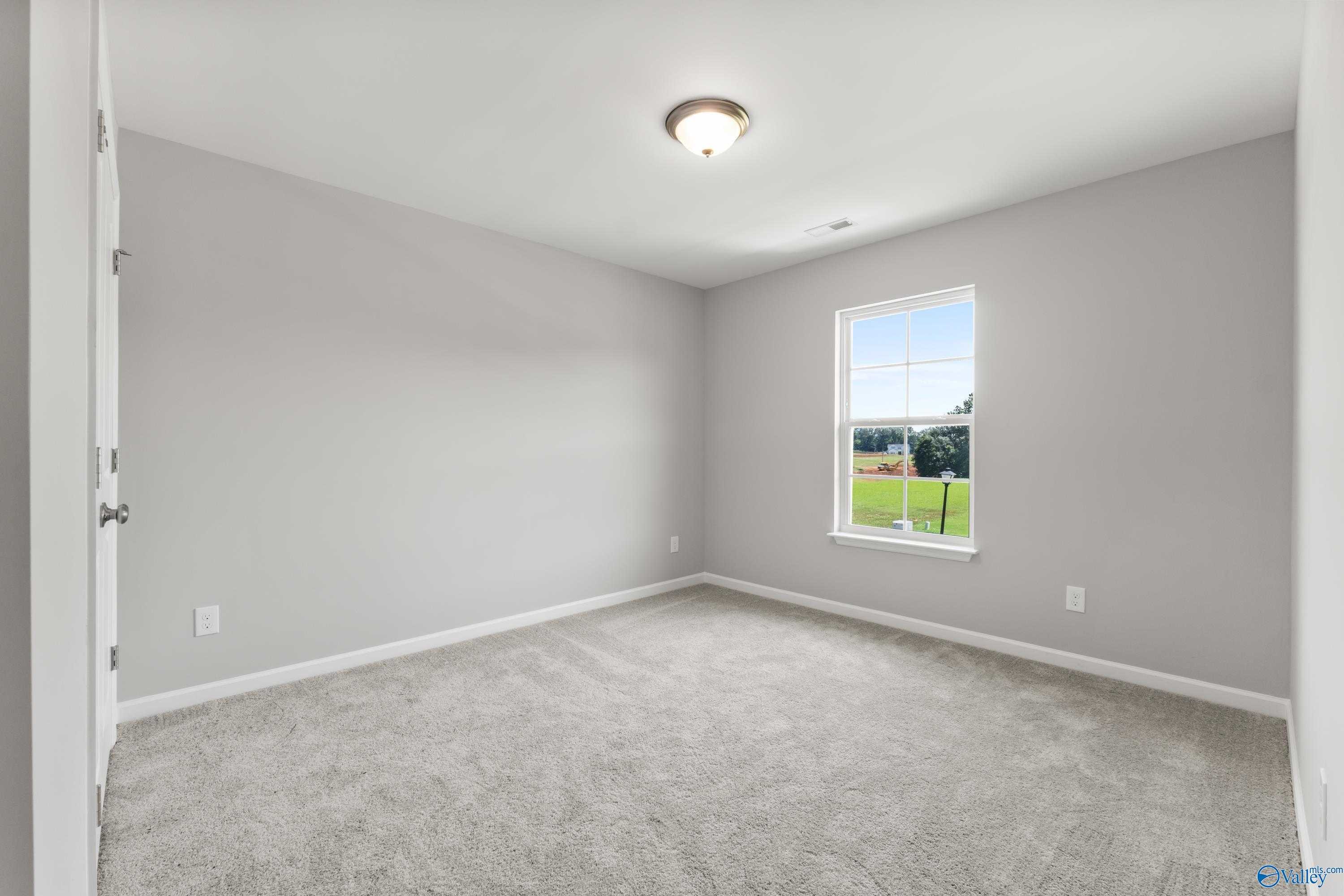 Bright secondary bedroom with light gray walls, beige carpet, and window view in Davidson Homes The Charm, Huntsville