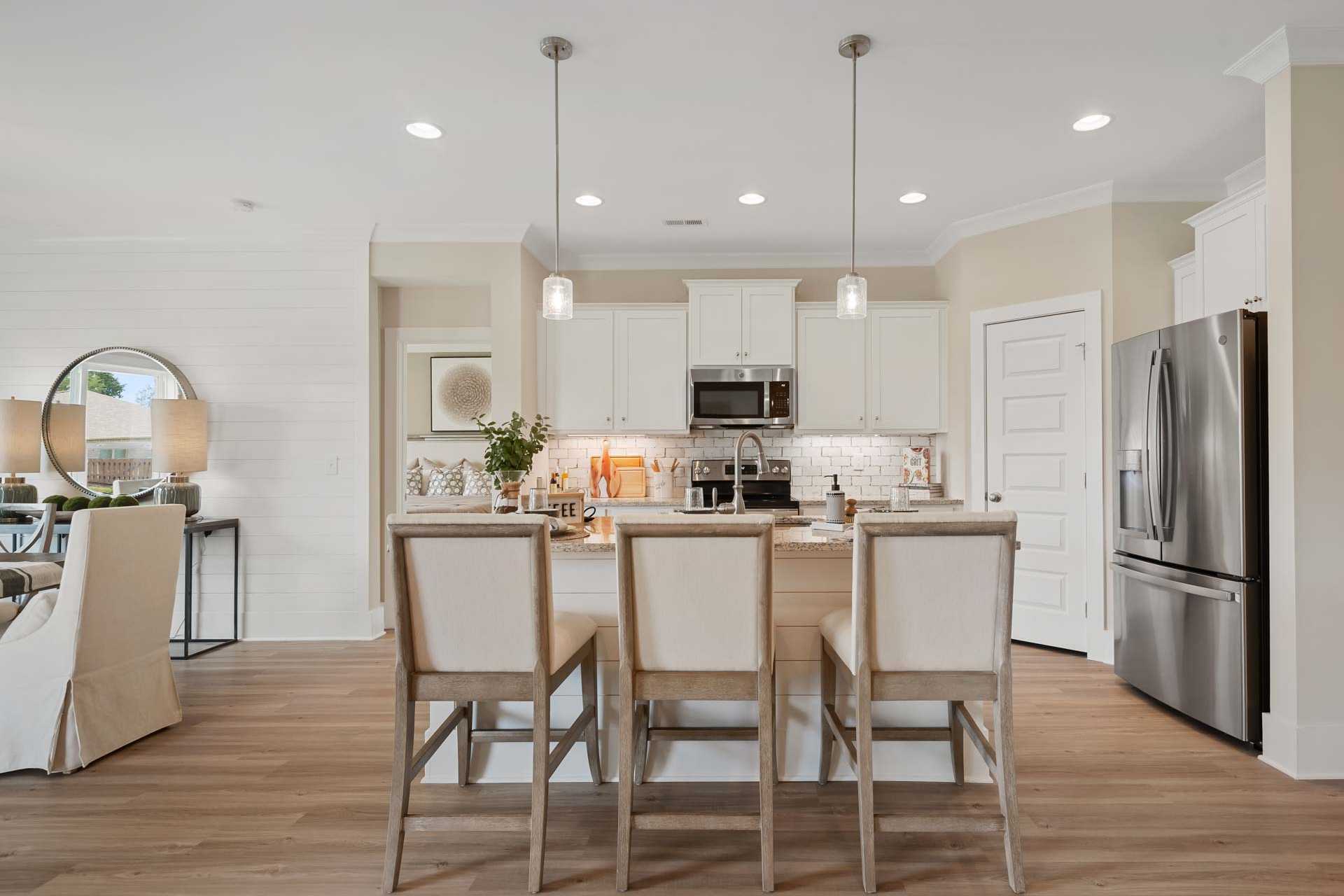 Spacious modern kitchen at Flint Meadows in New Market Alabama with white island bar stools hardwood floors and stainless appliances