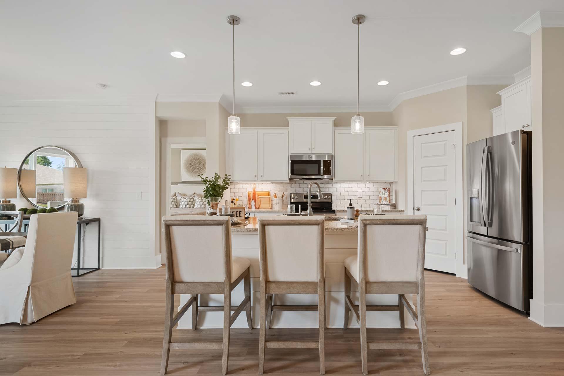 Spacious modern kitchen at Flint Meadows in New Market Alabama with white island bar stools hardwood floors and stainless appliances