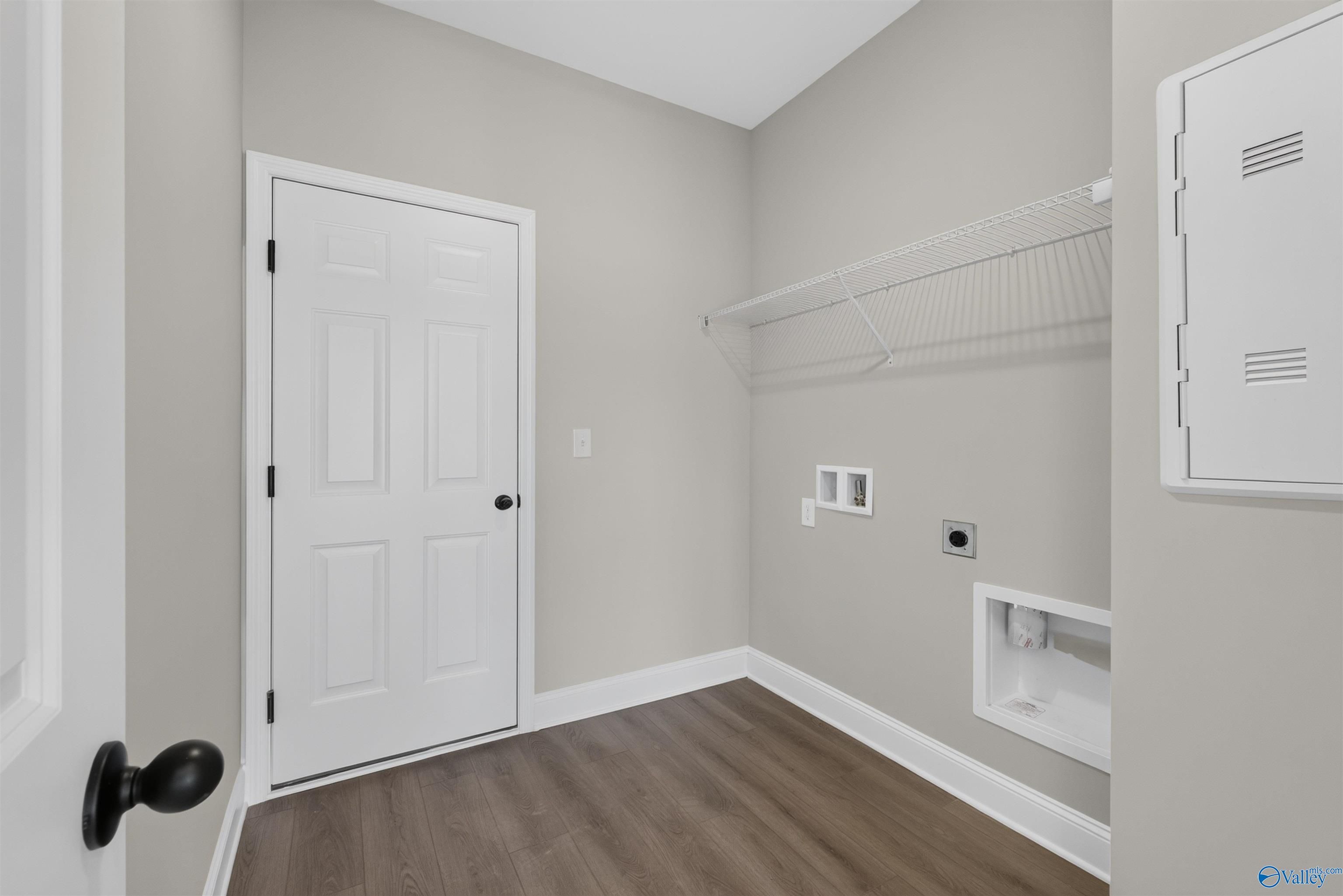 Laundry room with white door, wire shelving, and washer connections in Davidson Homes The Butler plan, Hazel Green, Alabama