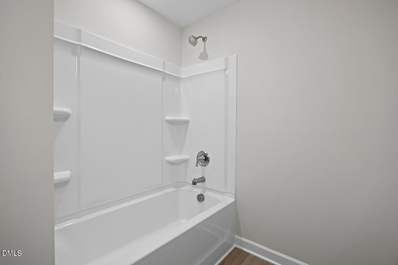 Modern full bathroom with white tub-shower combo in The Chestnut floor plan at Wendell Ridge, Wendell, North Carolina.