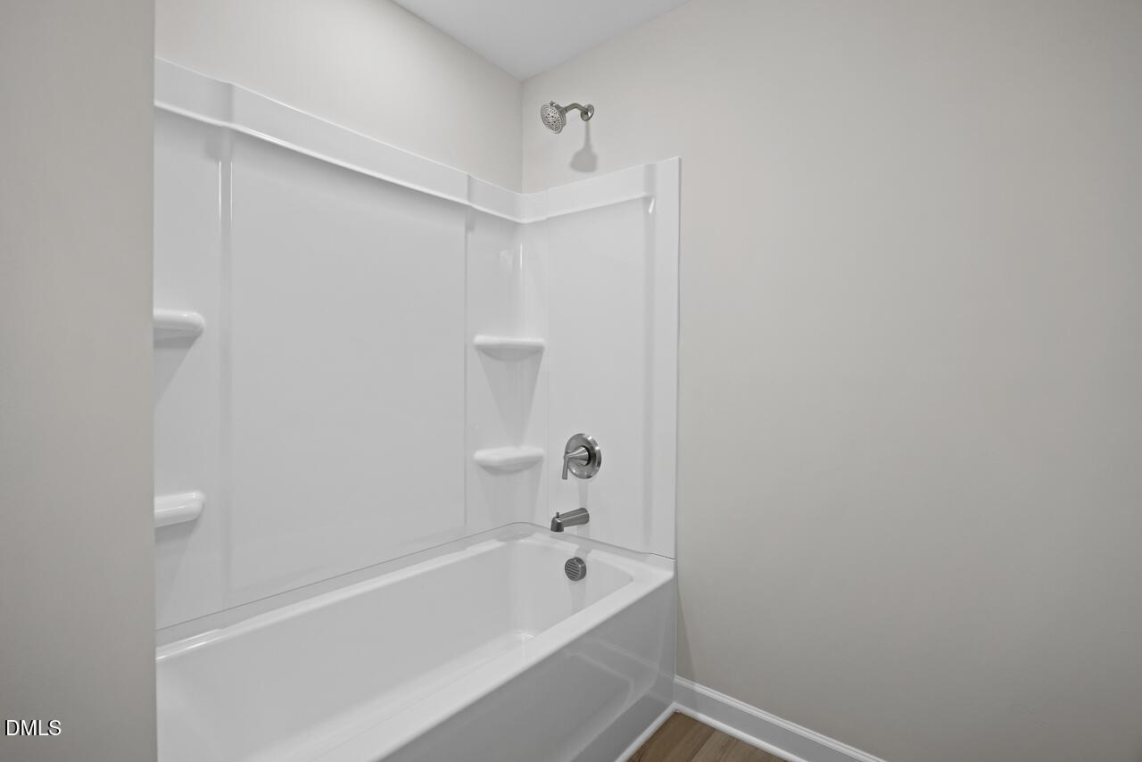 Modern full bathroom with white tub-shower combo in The Chestnut floor plan at Wendell Ridge, Wendell, North Carolina.