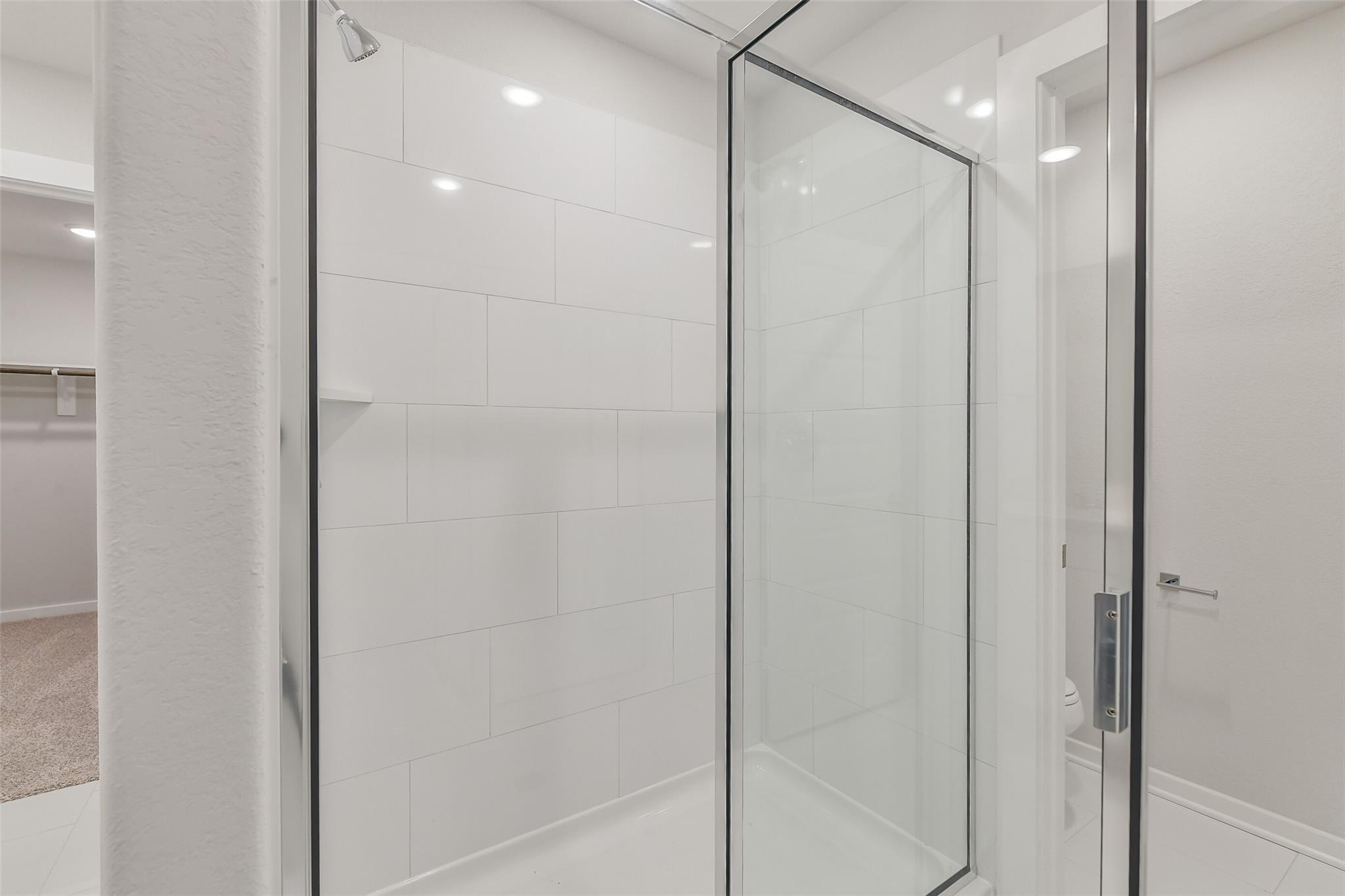 Modern frameless glass shower with white subway tiles in master bathroom, Davidson Homes The Trinity F, Magnolia Texas