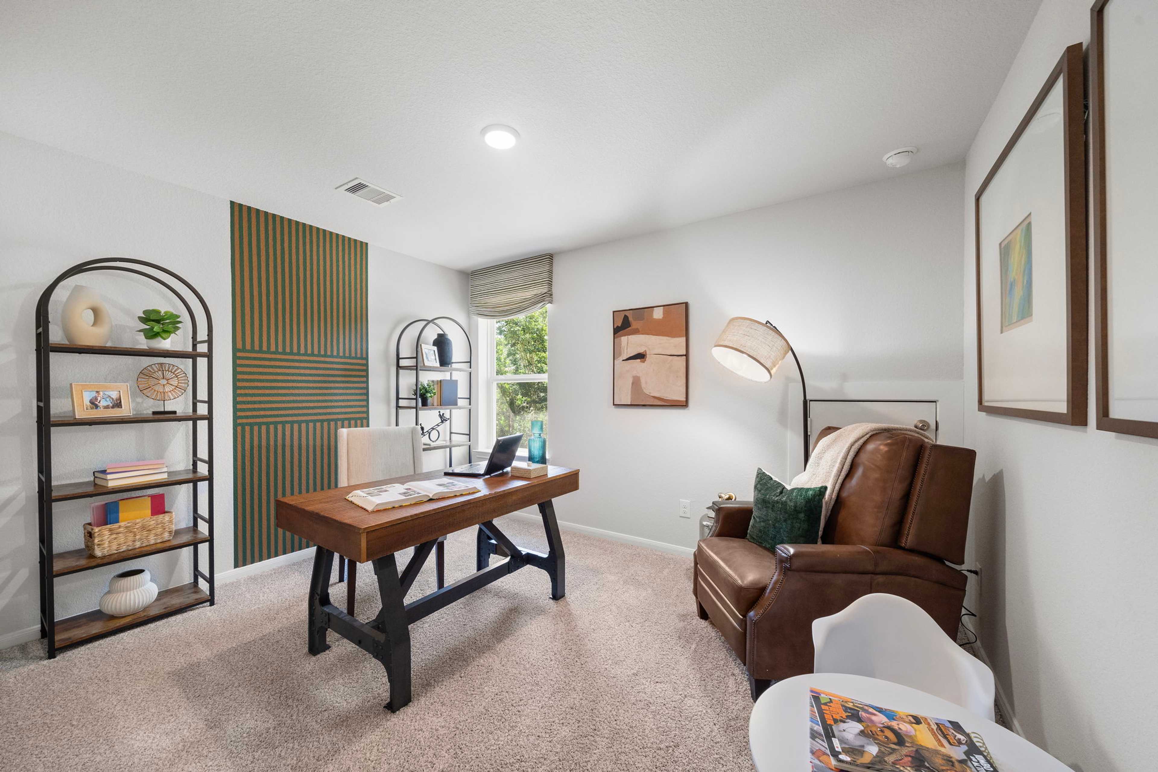 Cozy home office at Caney Creek Place in Conroe TX featuring rustic wooden desk, green accent wall, bookshelves, leather armchair
