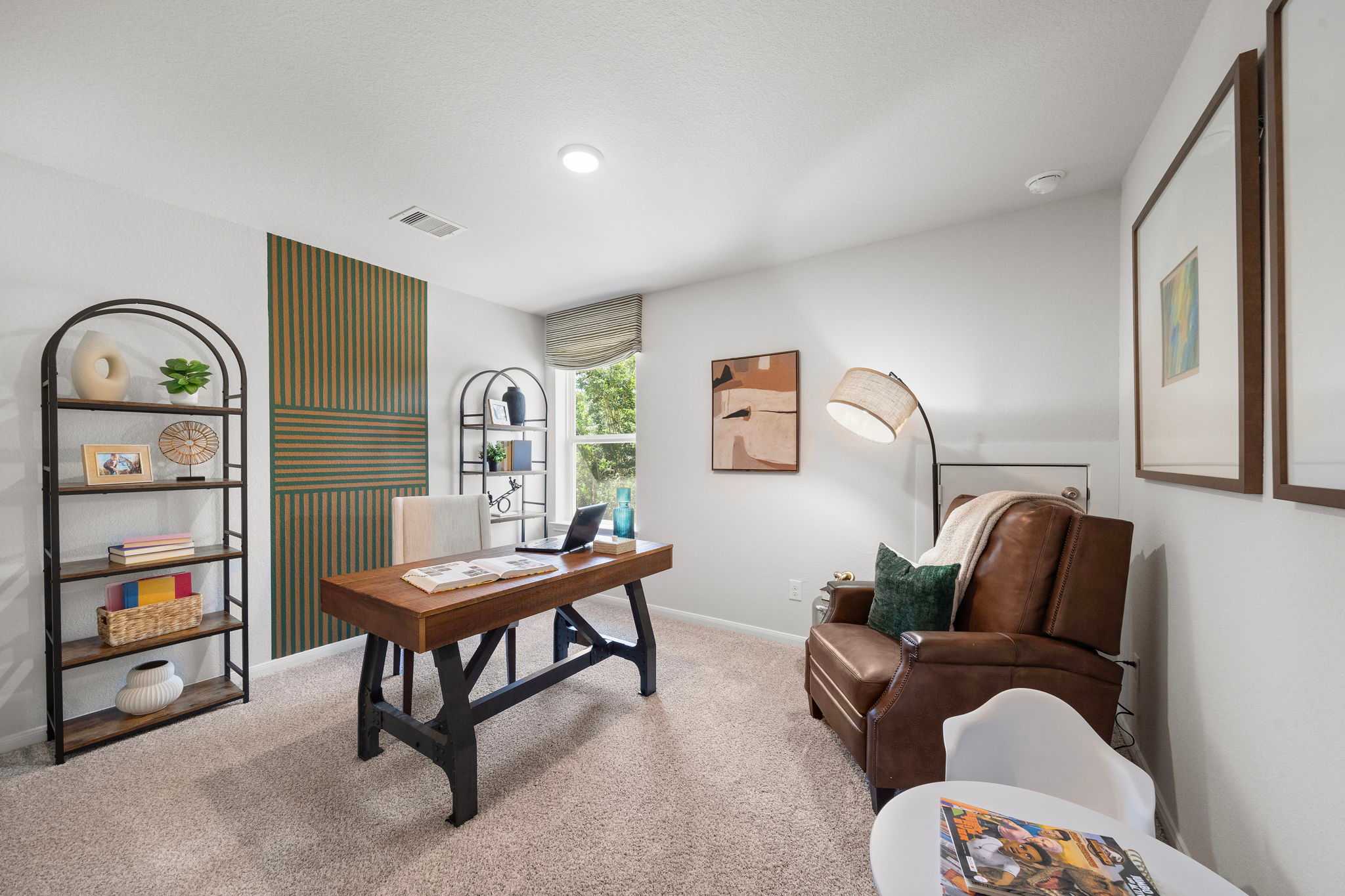 Cozy home office at Caney Creek Place in Conroe TX featuring rustic wooden desk, green accent wall, bookshelves, leather armchair
