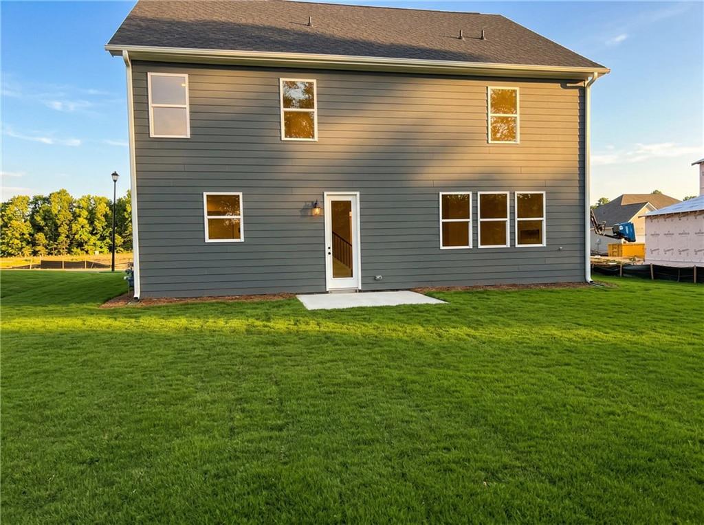Two-story gray home rear facade with large windows, covered back entry, and lush green backyard in Cedar Farms, Winder, Georgia