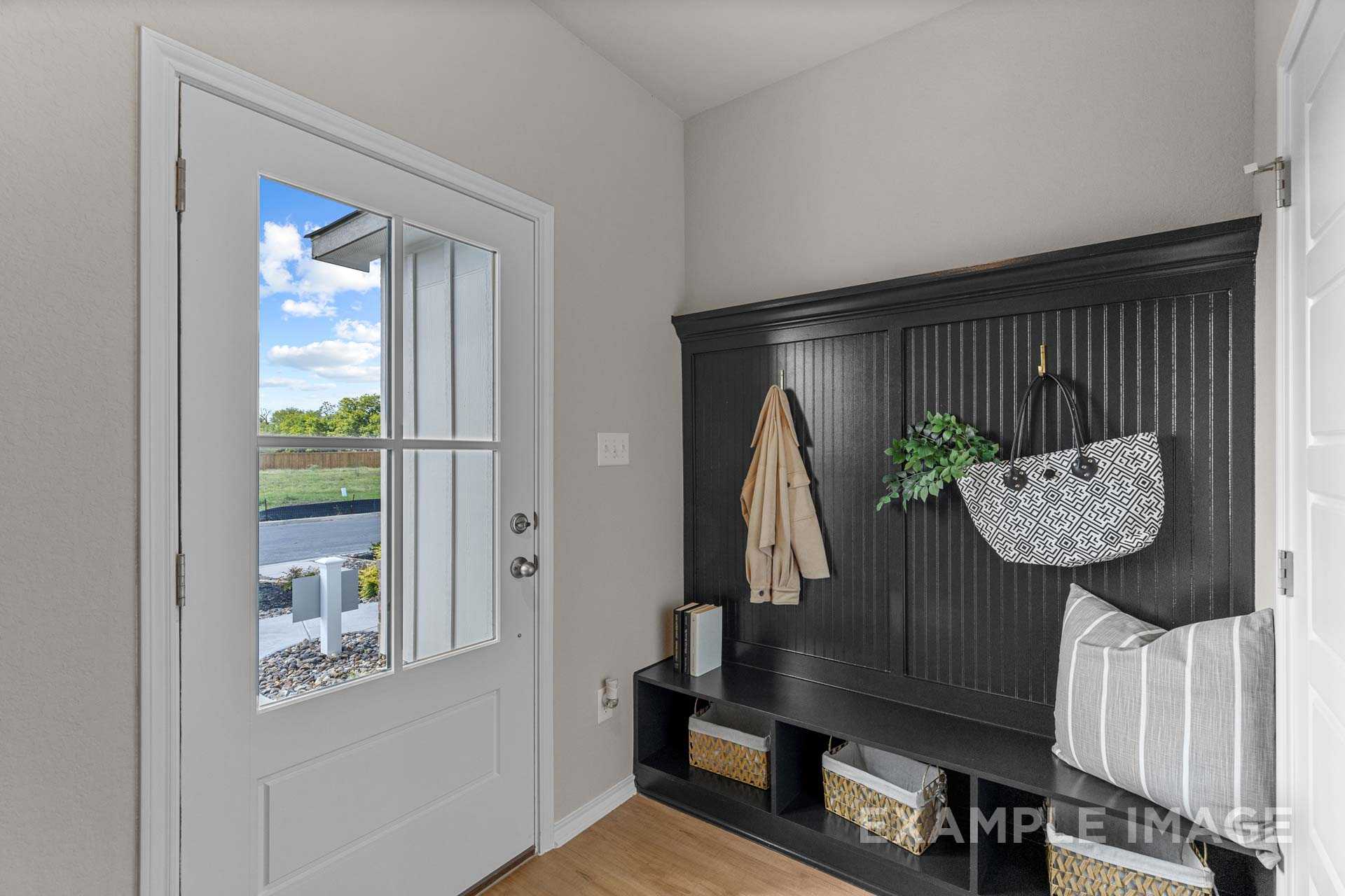 Bright entryway with built-in black coat storage, hooks, purses, and window view of lush yard in Davidson Homes Sabine B, San Antonio