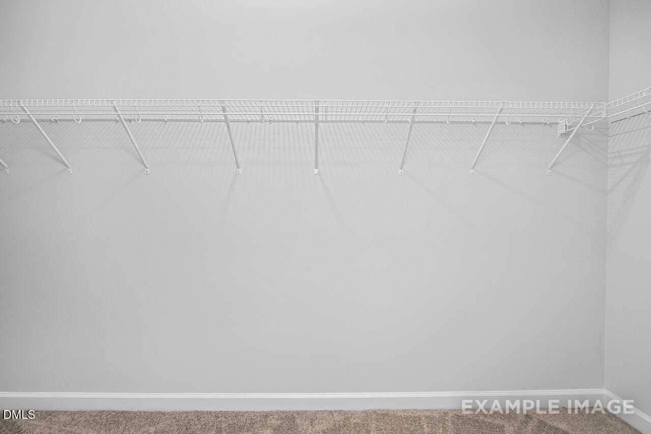 Spacious walk-in closet with white wire shelving and hanging rods in The Daphne C master suite, Davidson Homes, Lillington, NC