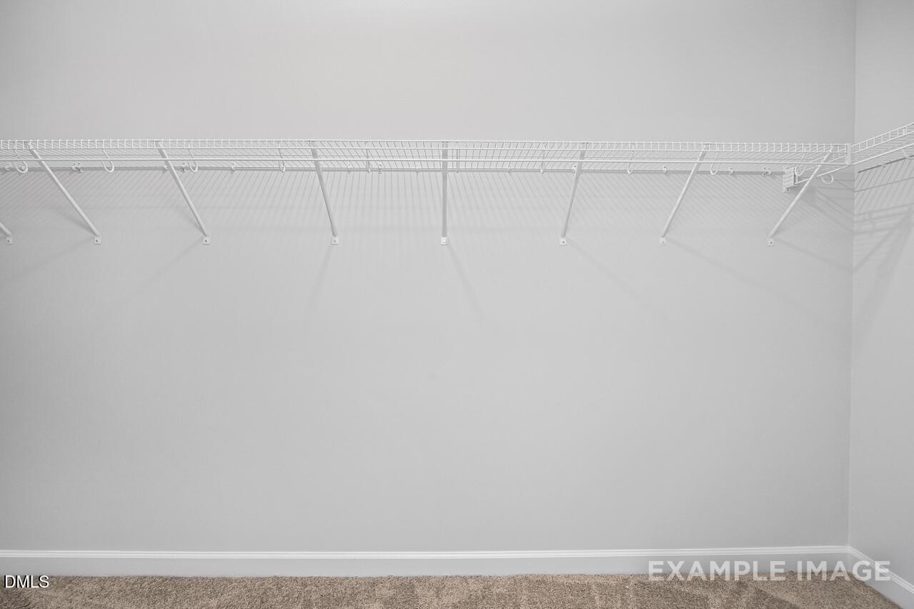 Spacious walk-in closet with white wire shelving and hanging rods in The Daphne C by Davidson Homes, Zebulon, NC