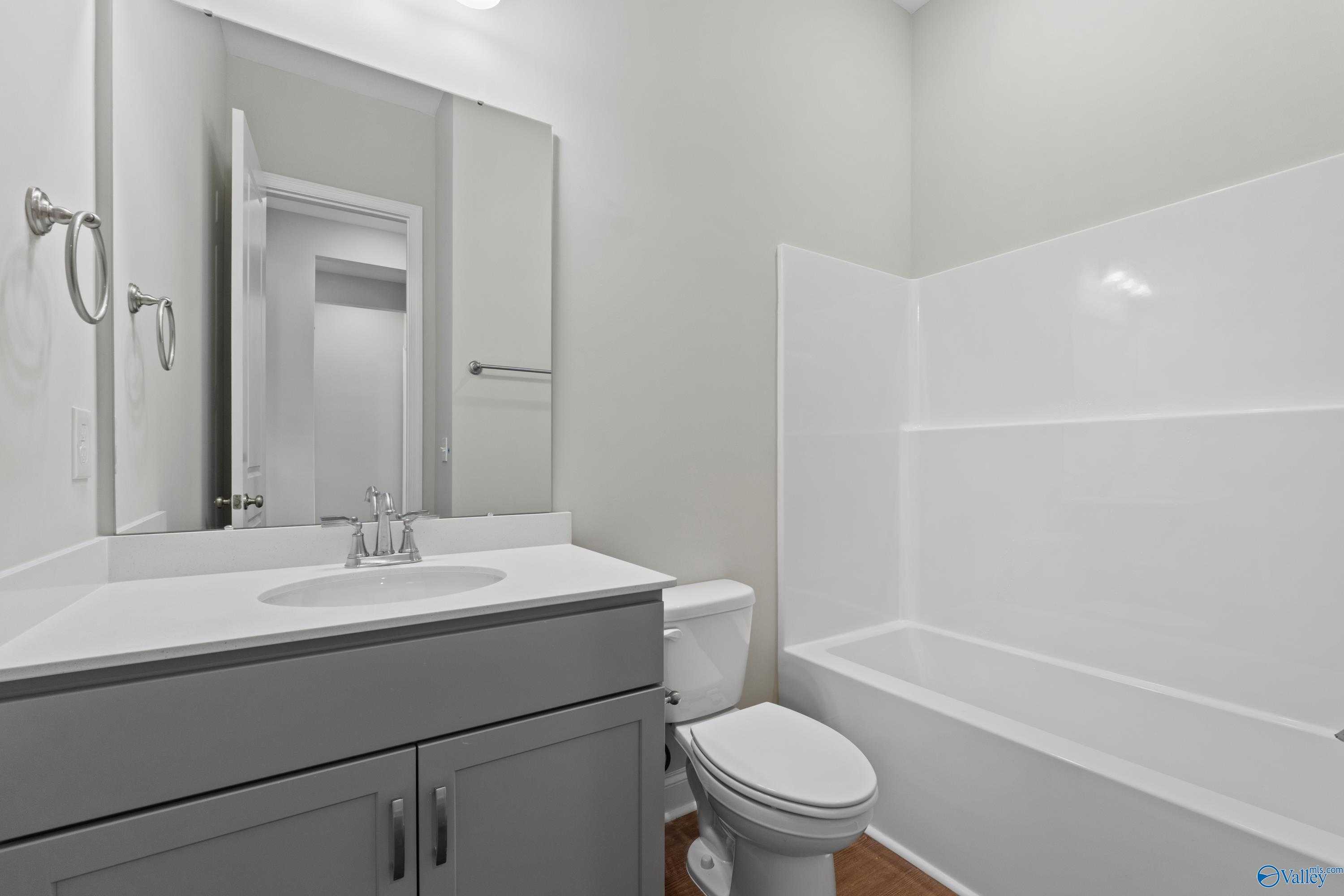 Modern bathroom with gray vanity, white tub-shower combo, and toilet in Davidson Homes The Arcadia, Huntsville, Alabama