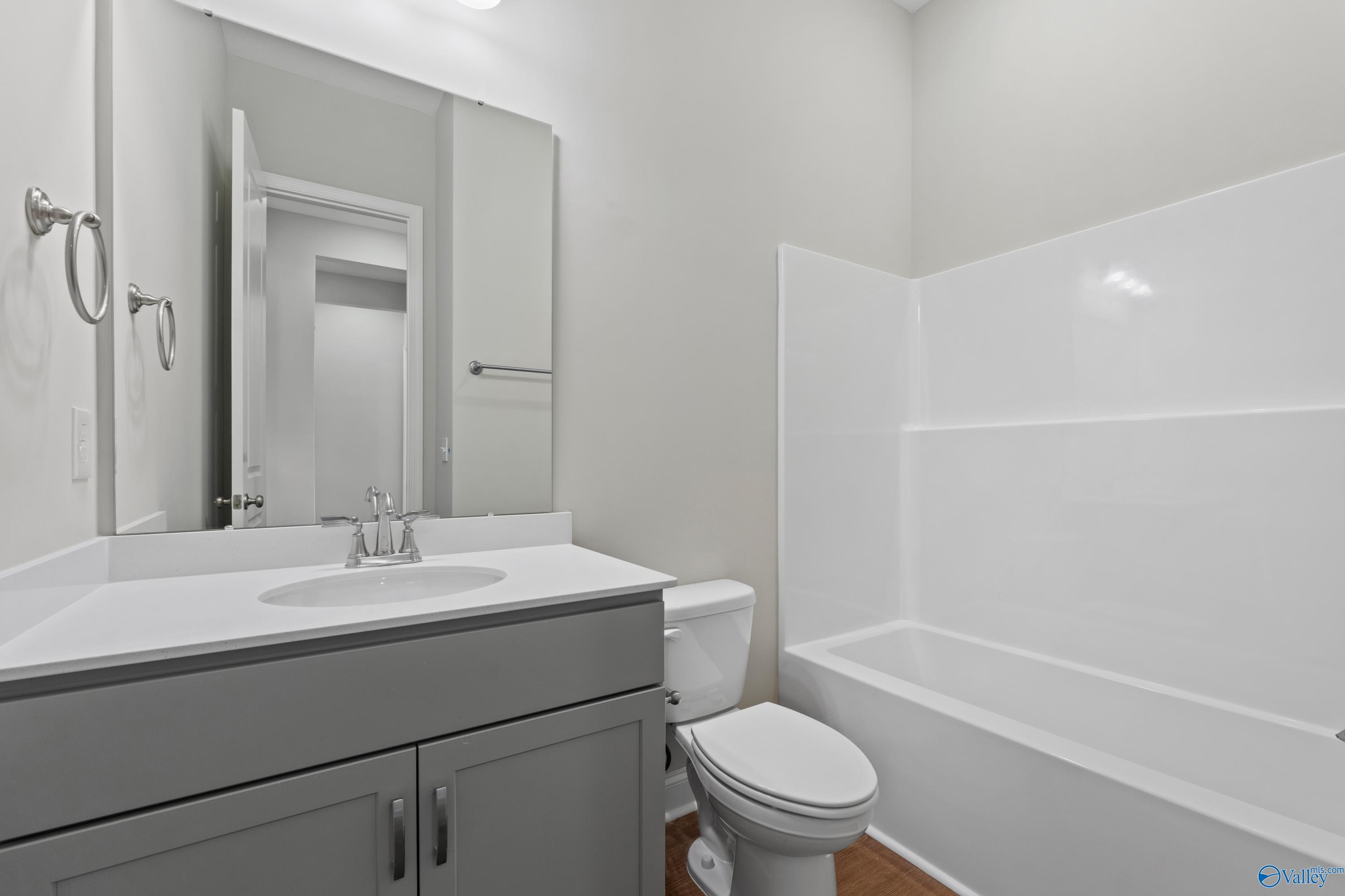 Modern guest bathroom featuring gray vanity, white tub-shower combo in Davidson Homes The Arcadia B, Huntsville, AL