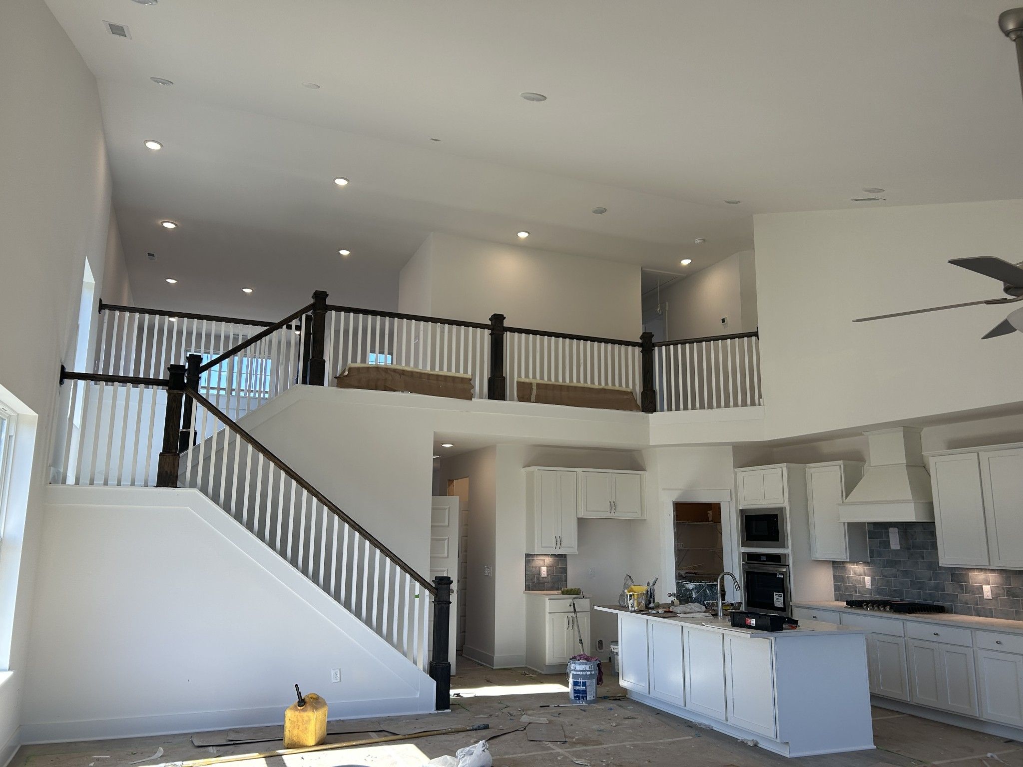 Two-story open interior with grand white staircase, black balusters, balcony overlook, and white kitchen cabinets in Davidson Homes Ridgeport D, Mt. Juliet, TN