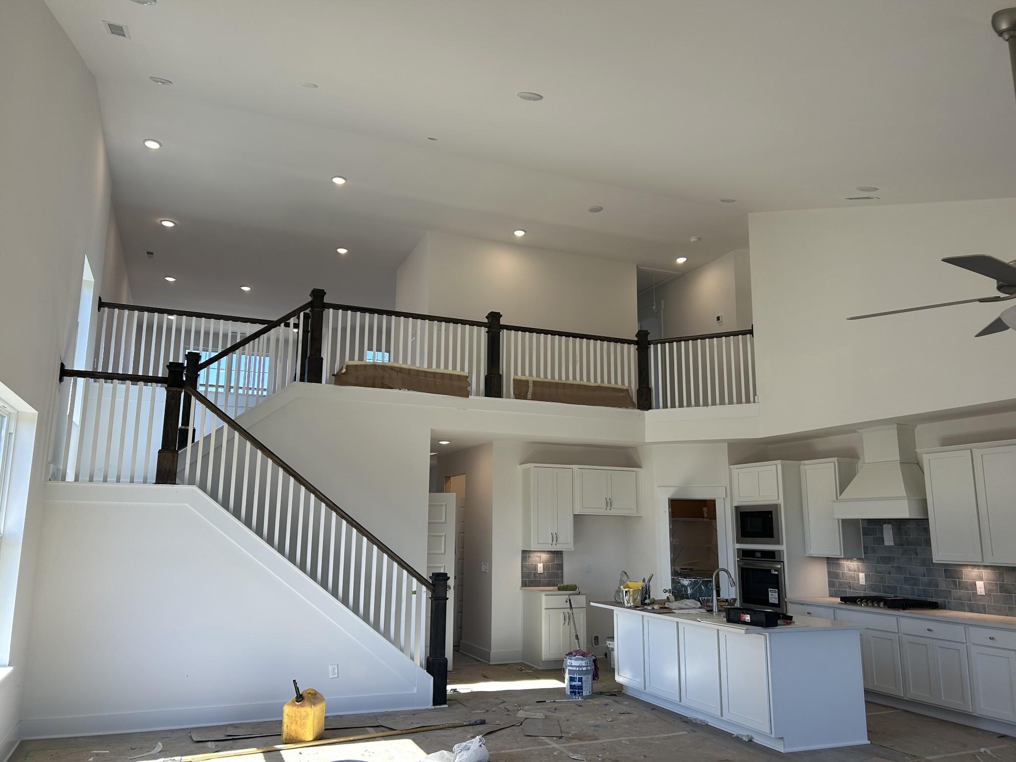 Two-story open interior with grand white staircase, black balusters, balcony overlook, and white kitchen cabinets in Davidson Homes Ridgeport D, Mt. Juliet, TN