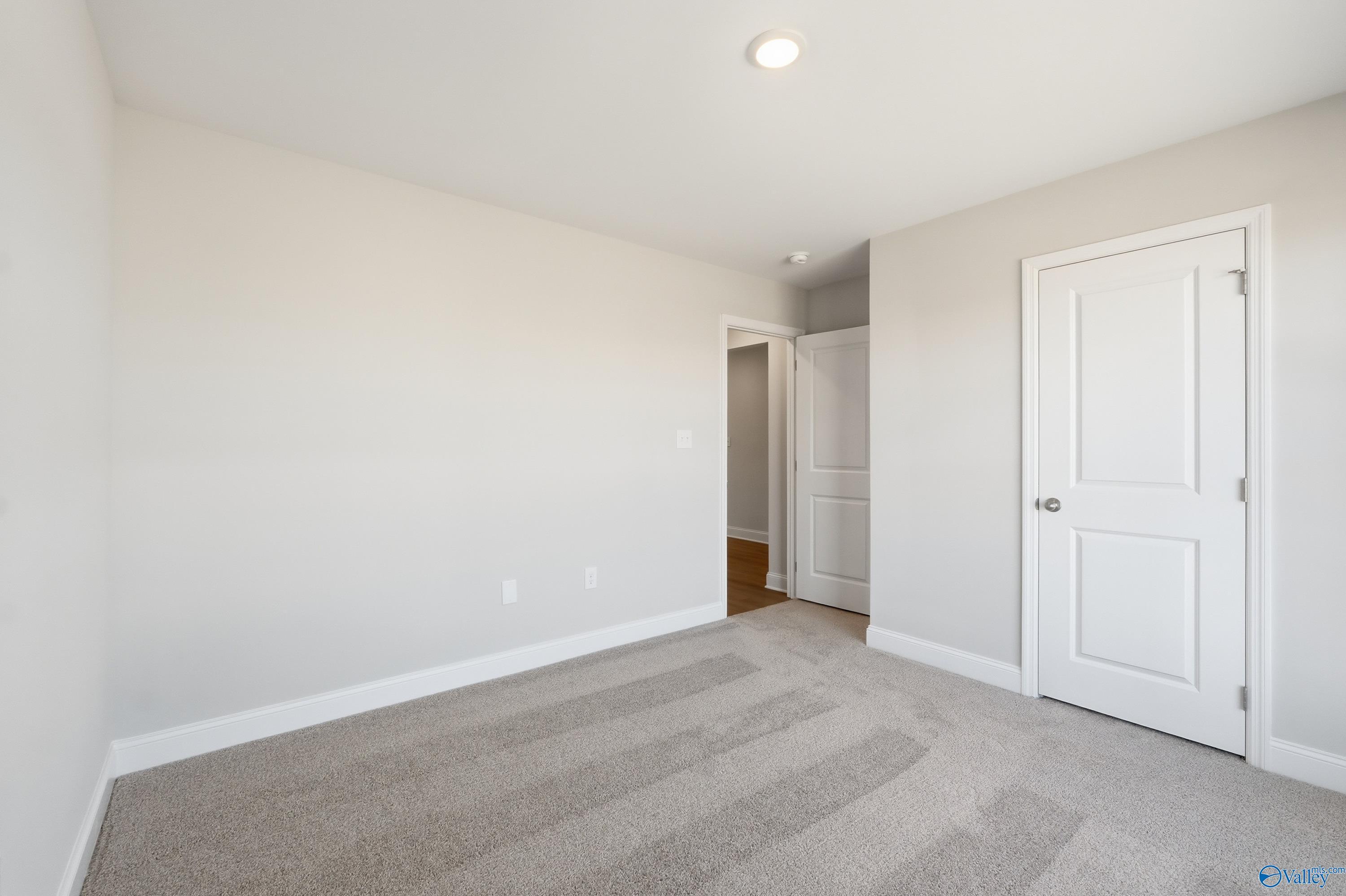 Spacious secondary bedroom with neutral beige walls, carpet flooring, and white doors in Davidson Homes The Franklin, Heritage Lakes