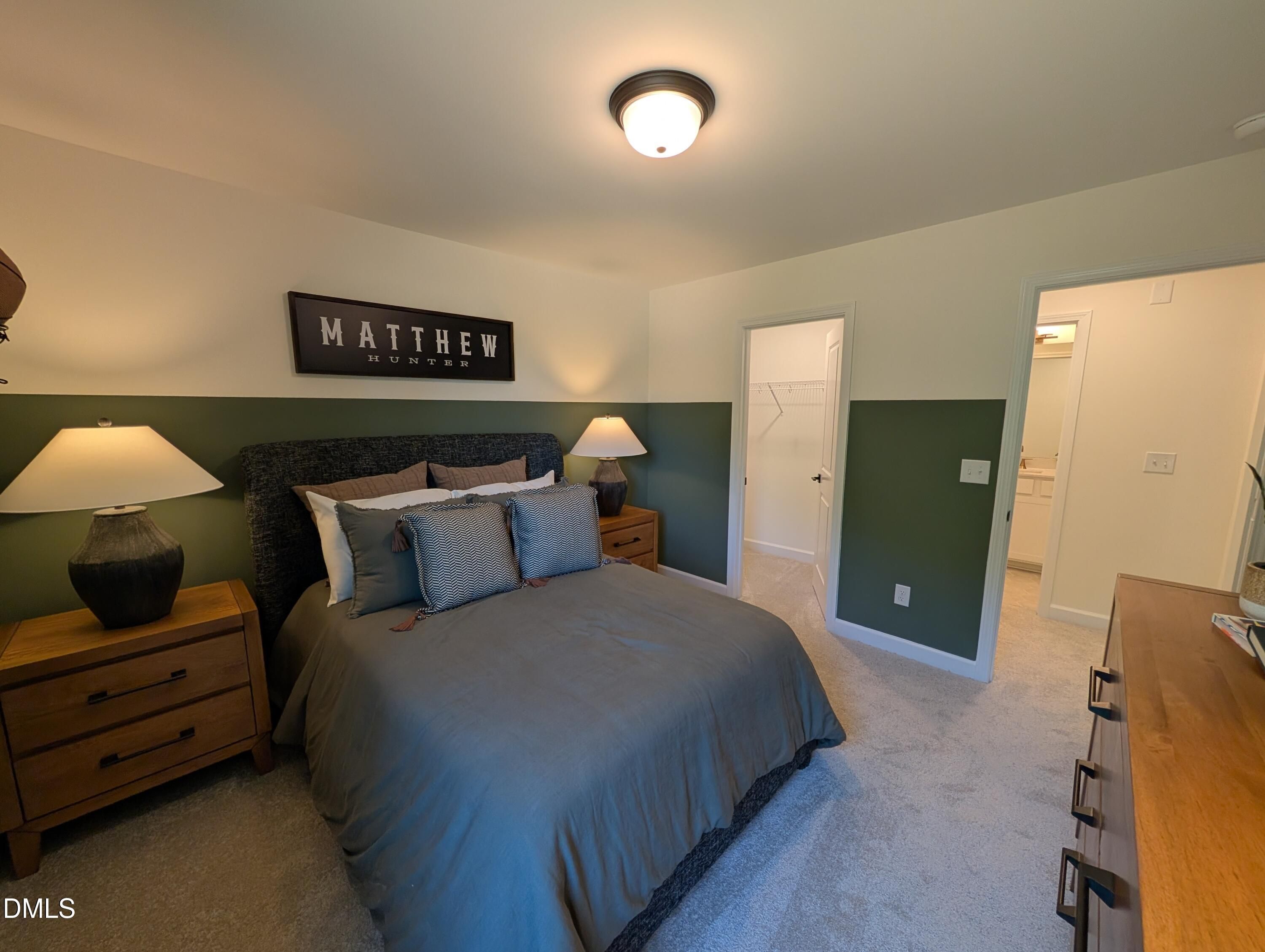 Cozy bedroom with green accent wall, walk-in closet, and ensuite bath in The Aspen B floor plan, Wendell Ridge, NC.