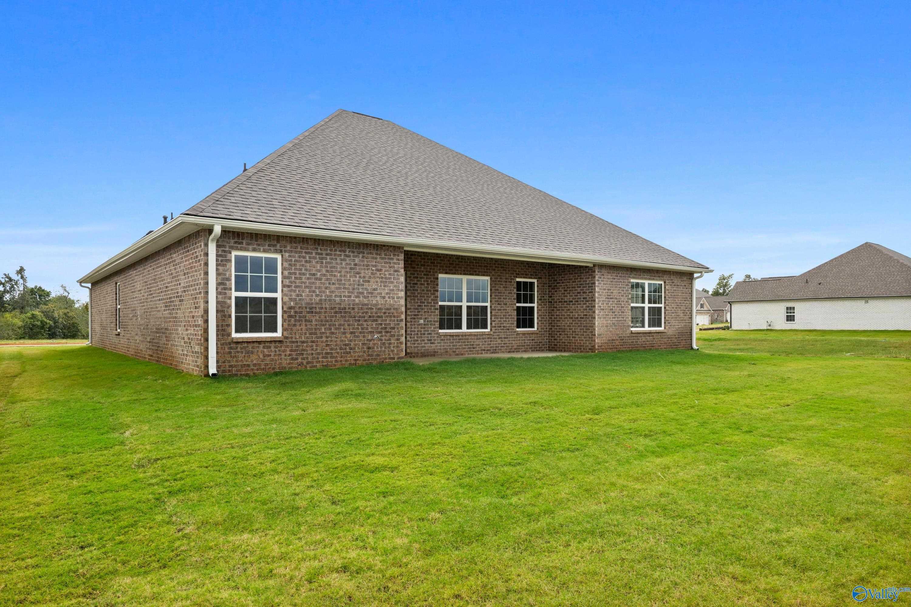 Brick single-story home exterior with gabled roof, large windows, and lush green yard in Creekside, Harvest, Alabama Davidson Homes The Lanier