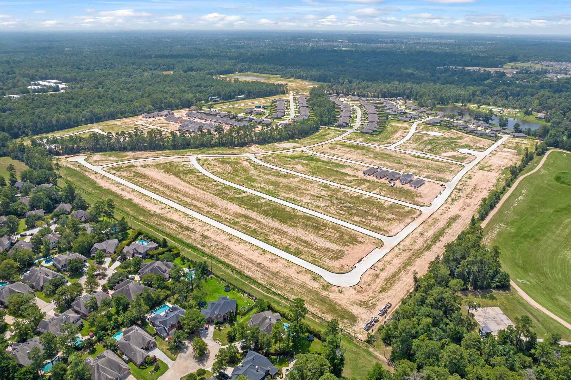 Aerial view of Lakes at Black Oak in Magnolia Texas with new home construction, dirt roads, and surrounding forests