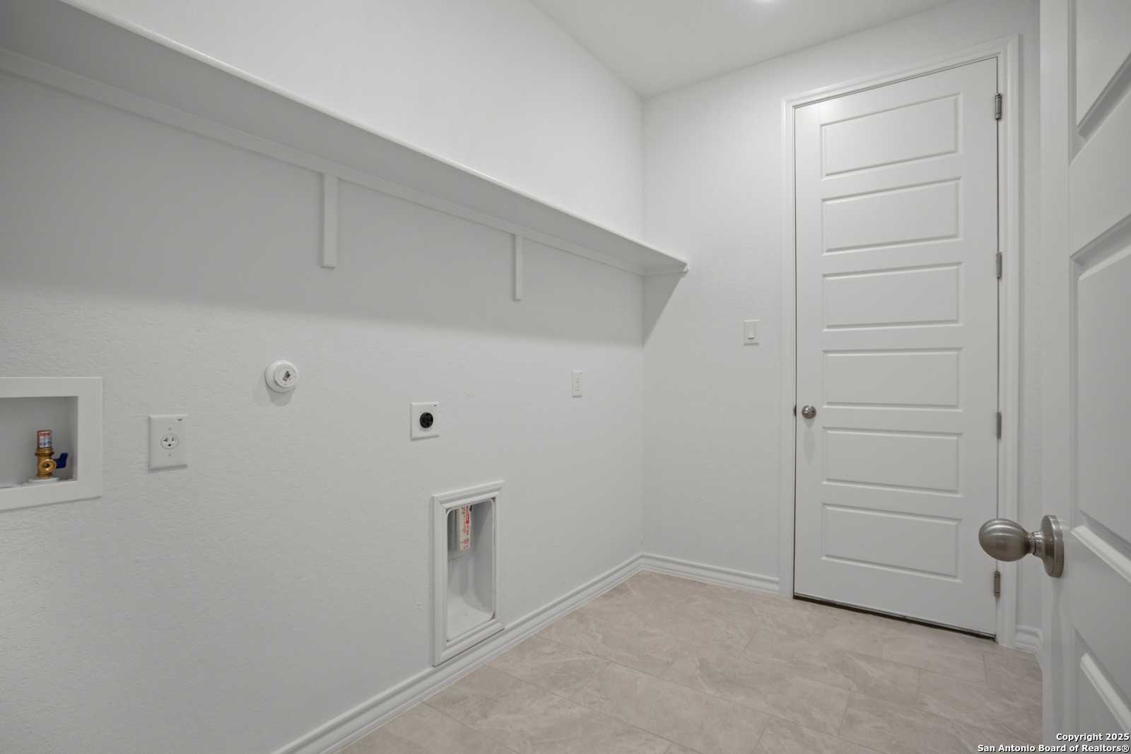 Spacious laundry room with built-in shelves, washer-dryer hookups and utility sink in Davidson Homes The Summerlin B, Castroville, Texas