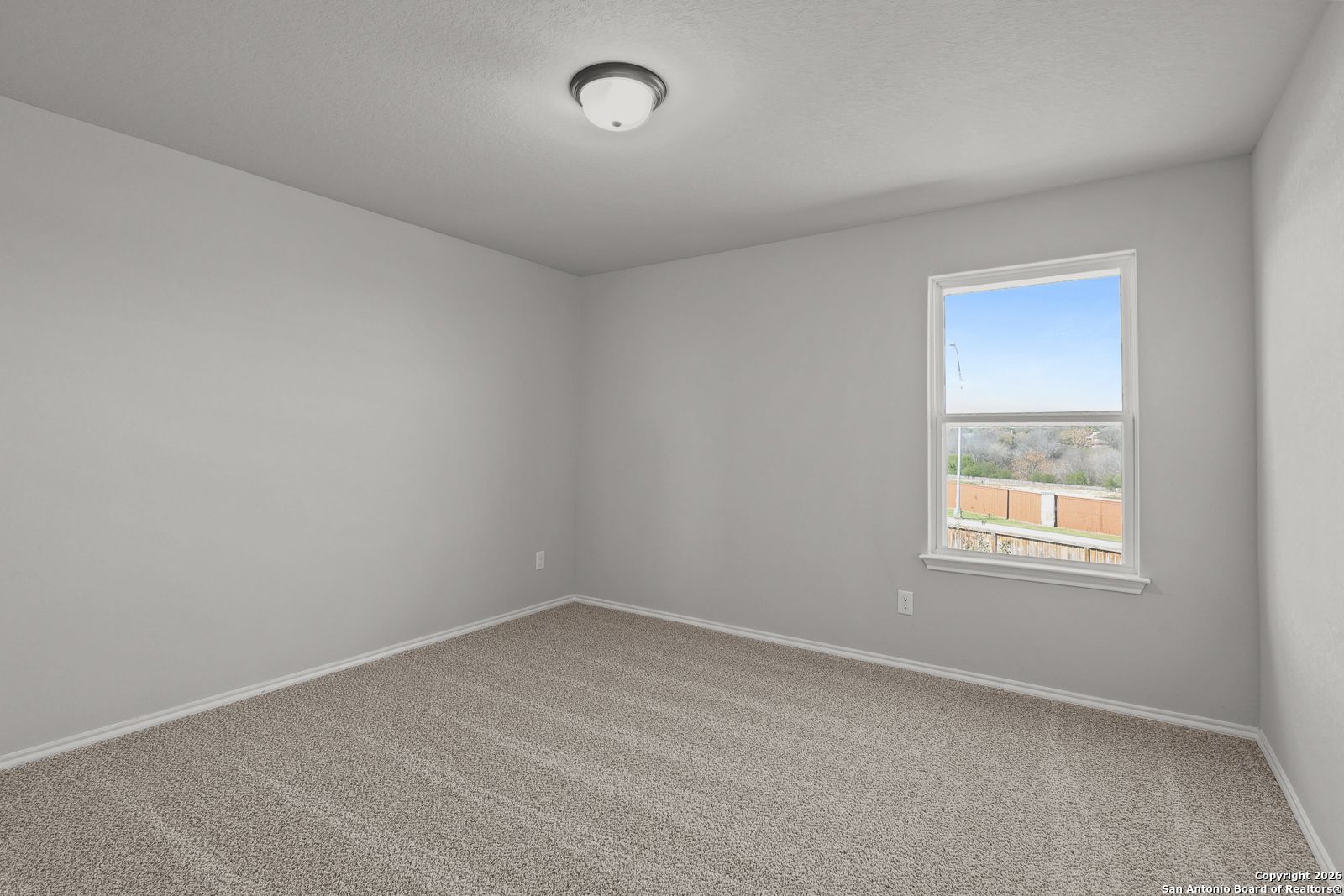 Empty bedroom with light gray walls, beige carpet, and large window view in 4-bedroom The Murray K home by Davidson Homes, San Antonio, Texas