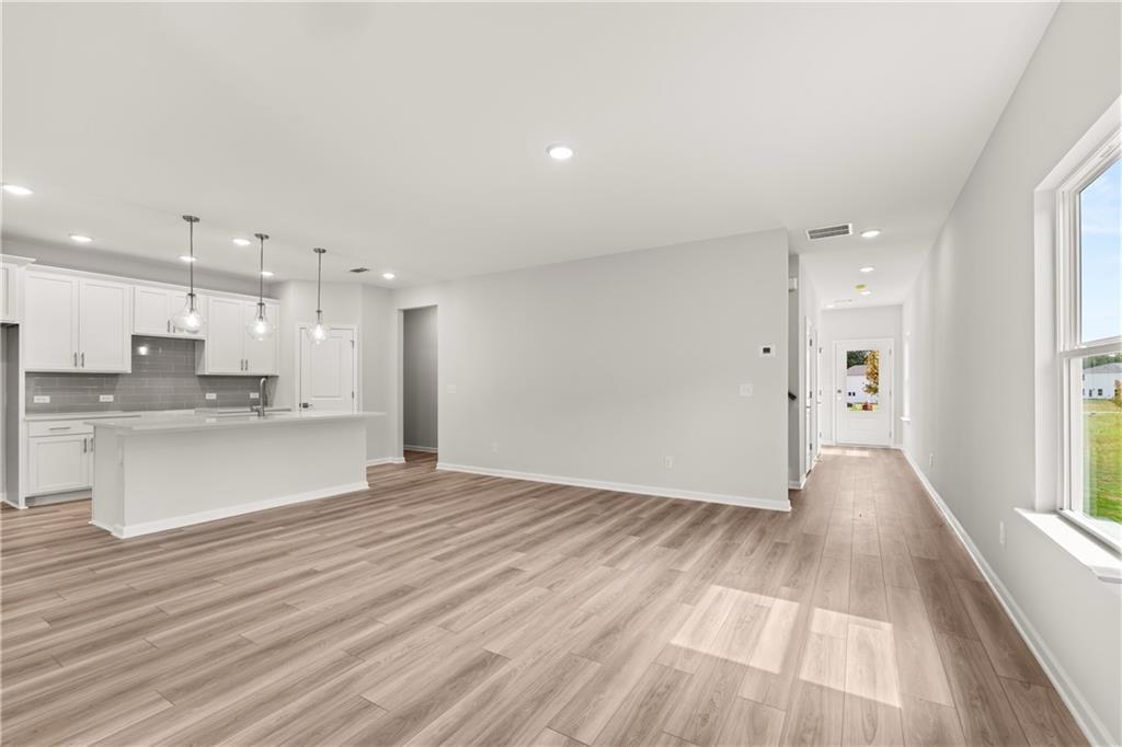 Open-concept kitchen and living area with luxury vinyl plank flooring in The Russell A floor plan at Cedar Farms, Winder.