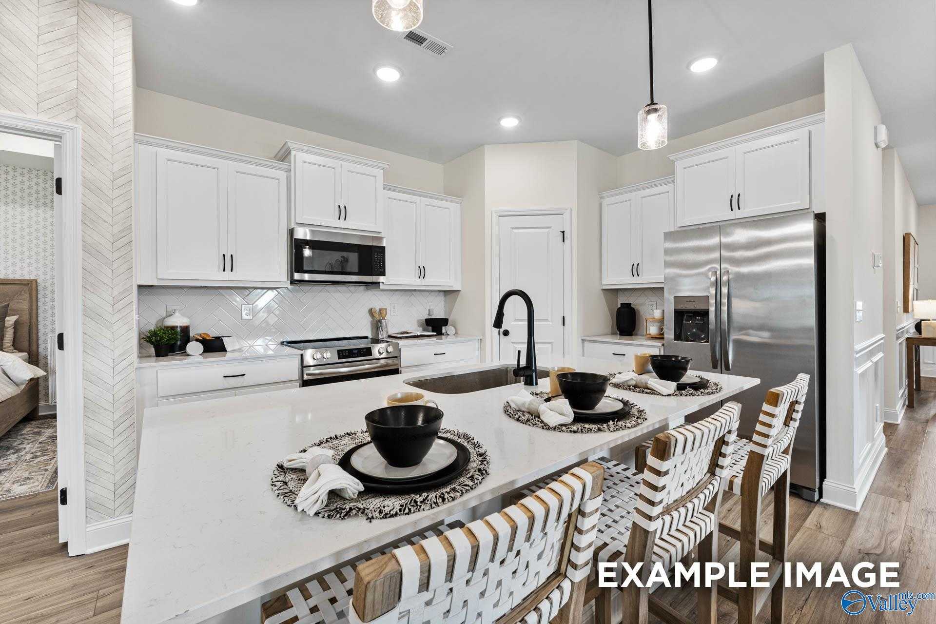 Modern open-concept kitchen with white shaker cabinets, stainless appliances, and island bar in Davidson Homes The Franklin, Huntsville