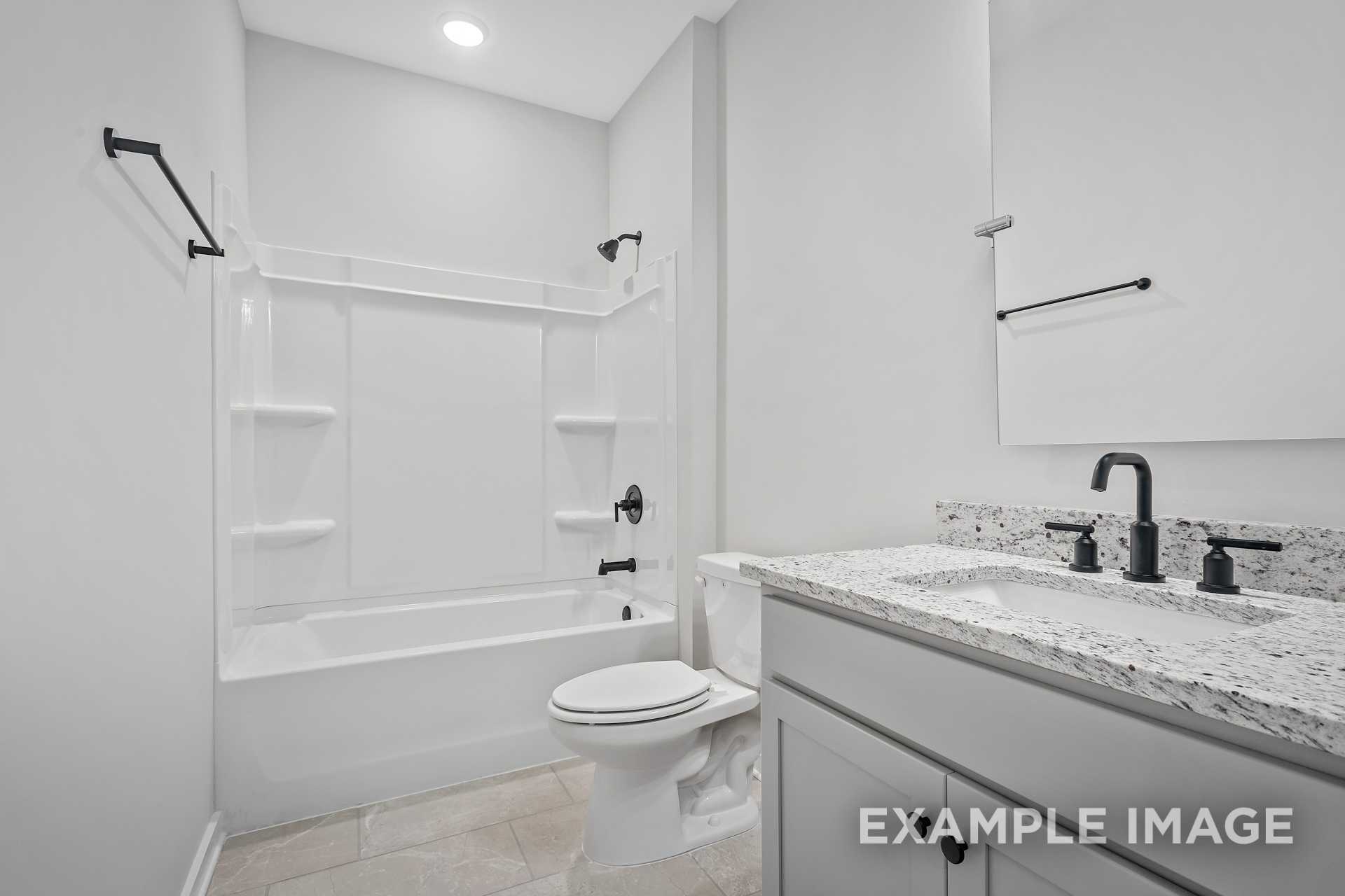 Modern bathroom in The Hathaway featuring white tiled walk-in shower, alcove soaking tub, gray vanity with quartz countertop, black fixtures