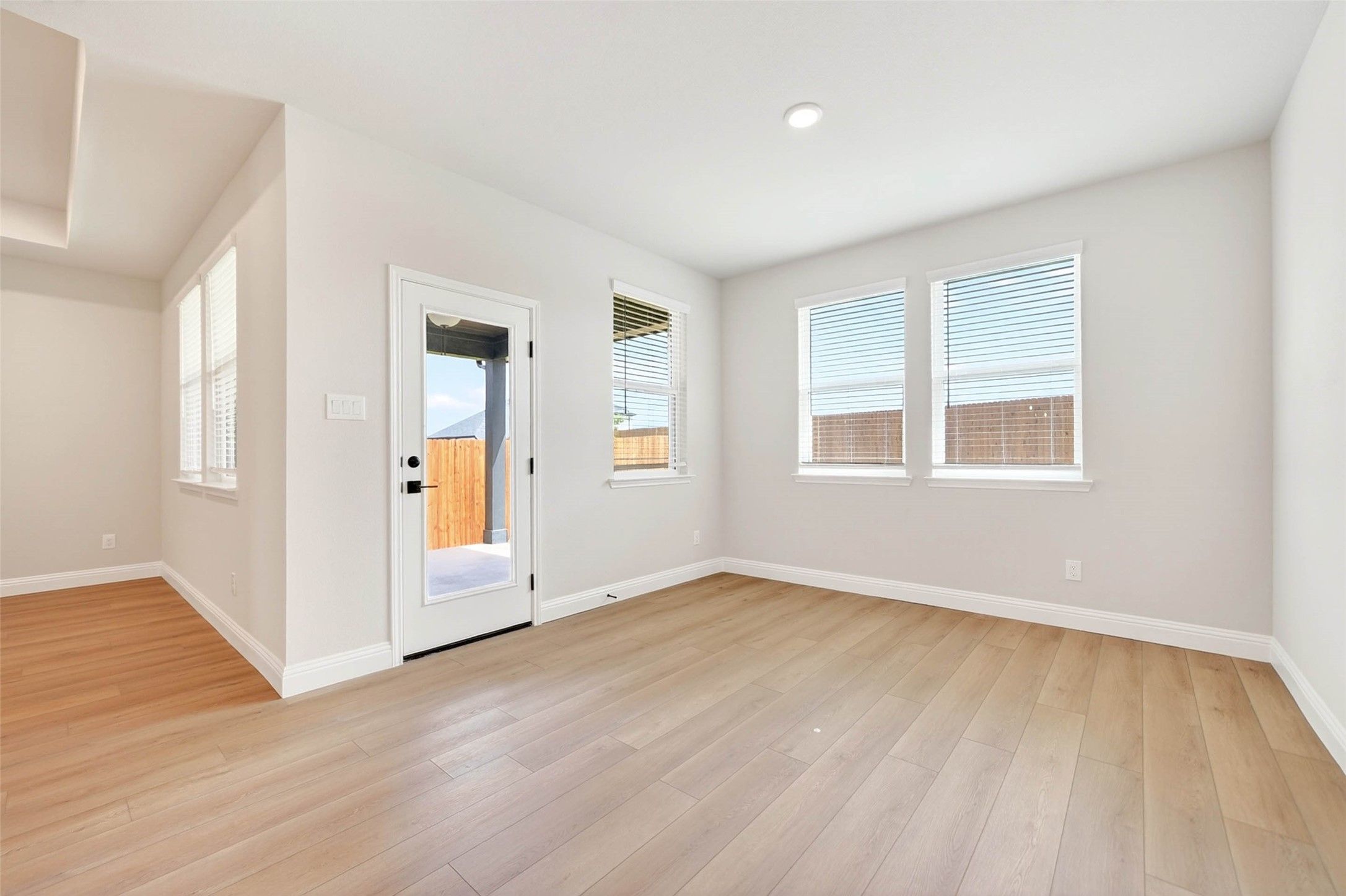 Bright, neutral living space with hardwood-style flooring and patio access in The Holly C floor plan, Anna, Texas.