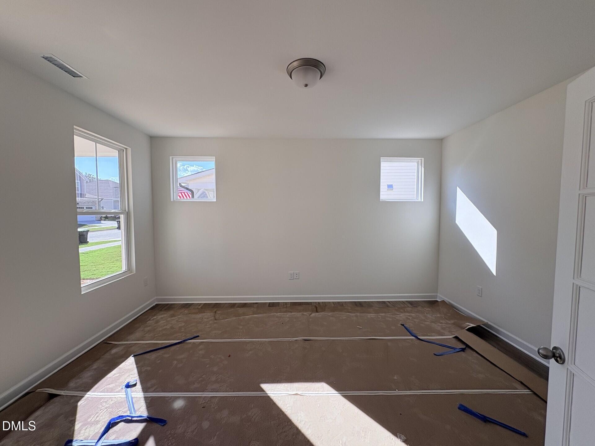 Bright empty bedroom with windows and protective floor covering in new Davidson Homes Hickory II B, Woodland Crossing, Zebulon NC
