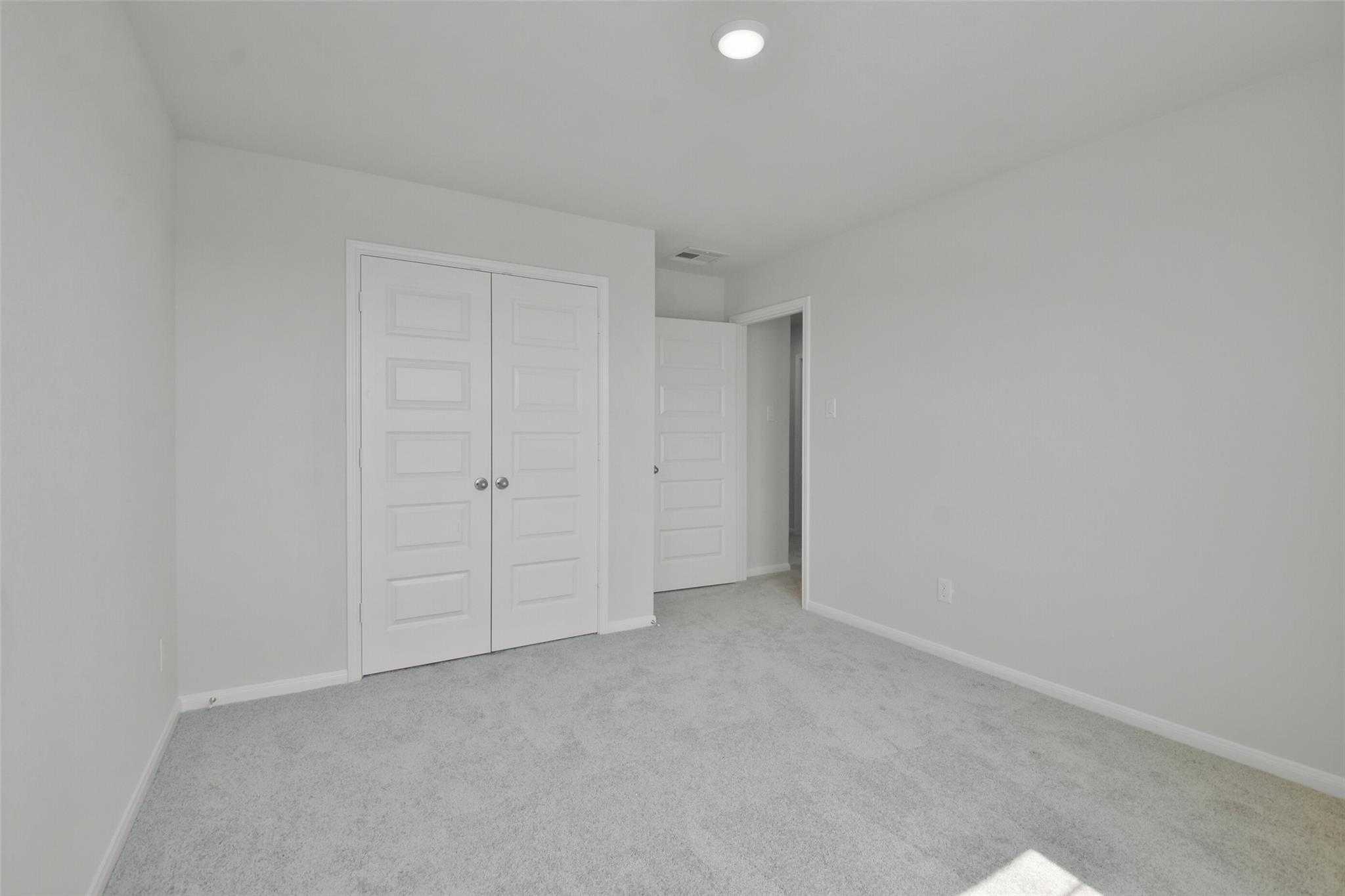Spacious secondary bedroom featuring double closet doors and adjacent bath in Davidson Homes The Tierra A, Dayton, Texas