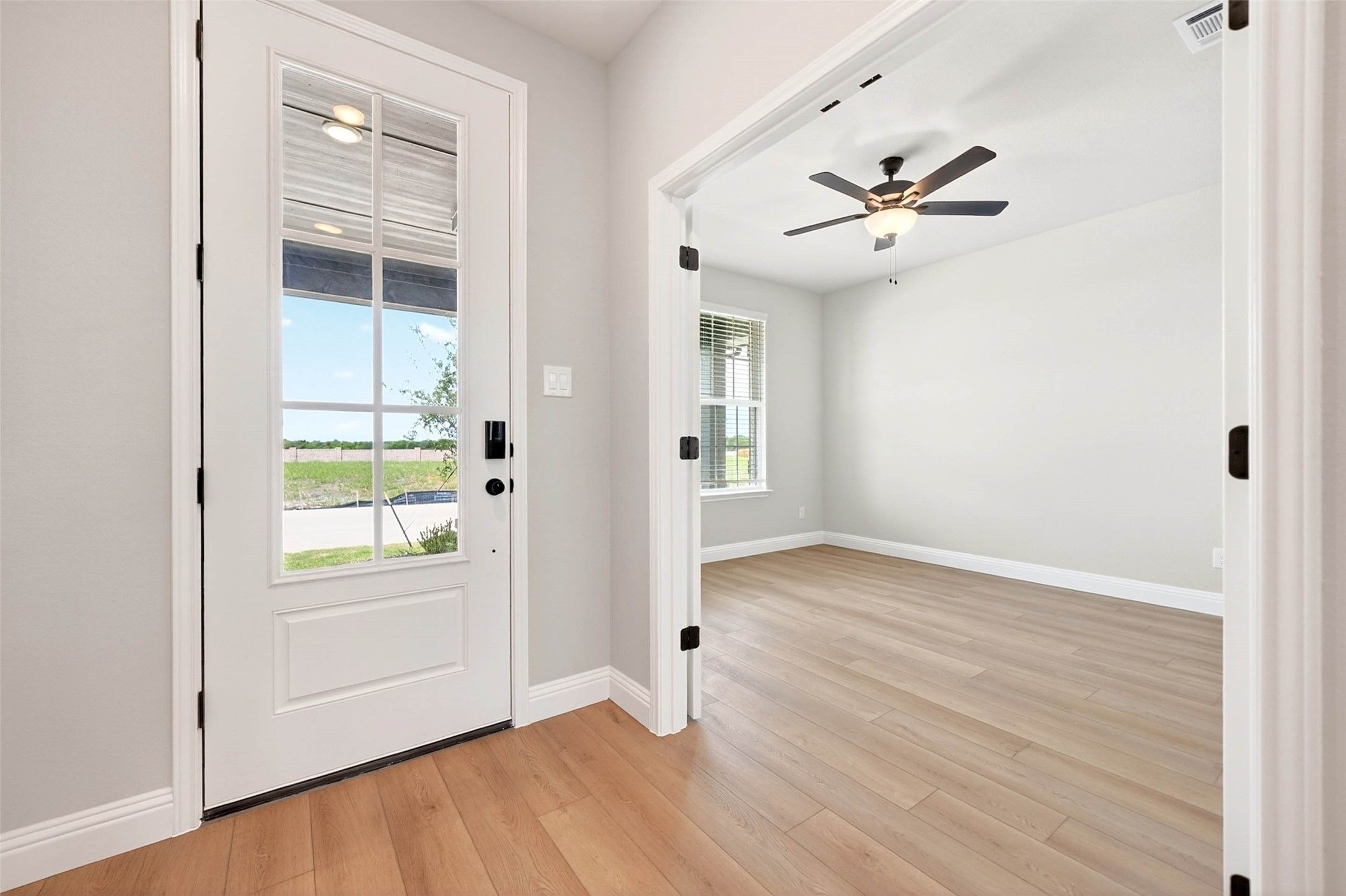 Bright entryway with glass-paneled front door leading into a bedroom in The Holly C floor plan, Parks at Foster Crossing.