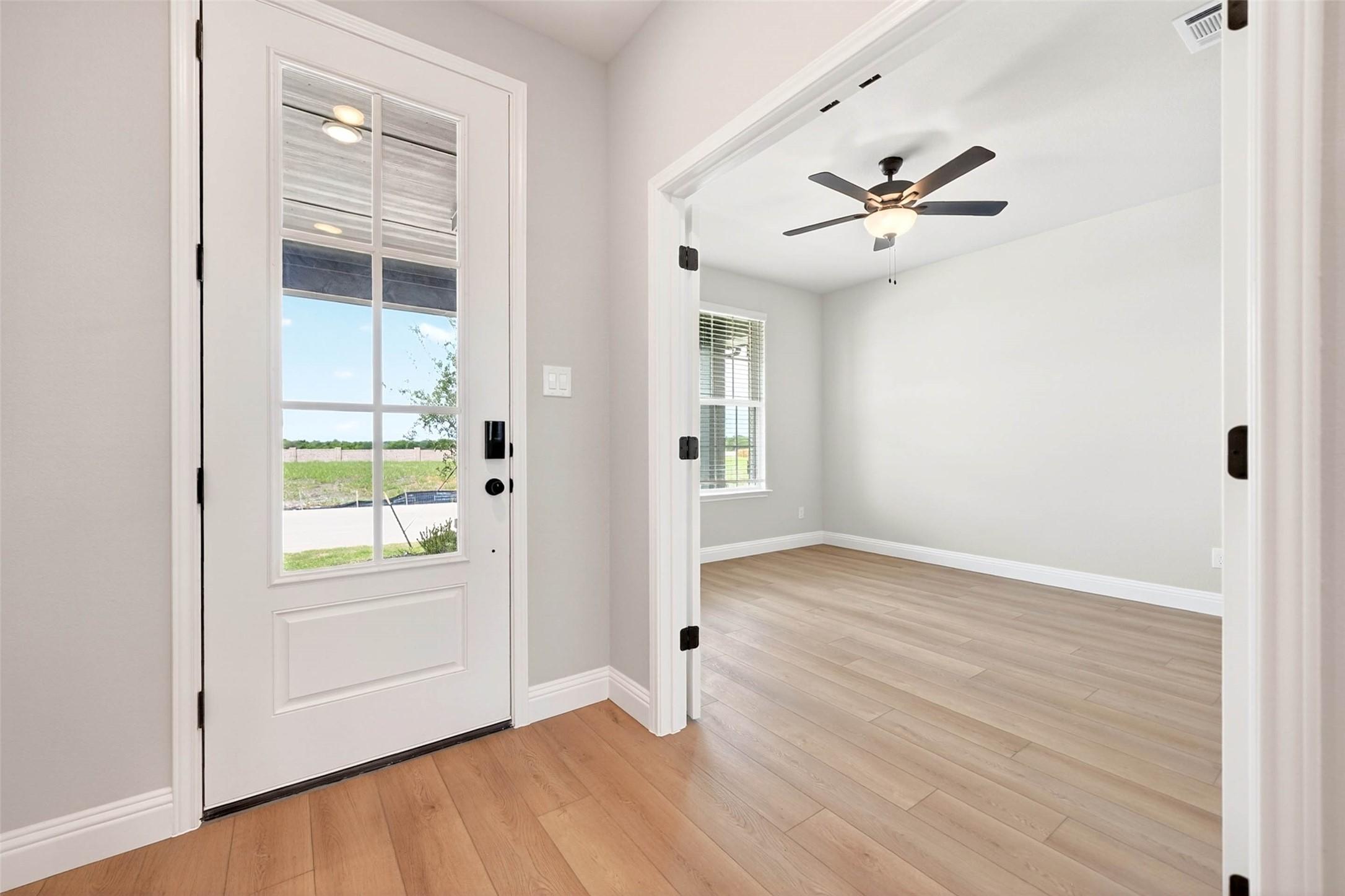 Bright entryway with glass-paneled front door leading into a bedroom in The Holly C floor plan, Parks at Foster Crossing.