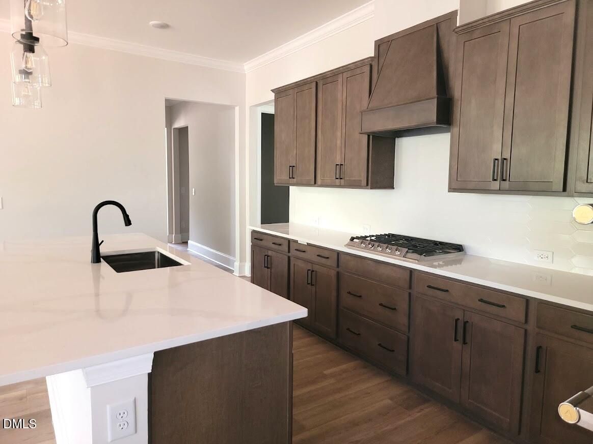 Kitchen island with white quartz countertop, dark wood cabinets, and gas cooktop in Davidson Homes Magnolia II B, Wake Forest, NC