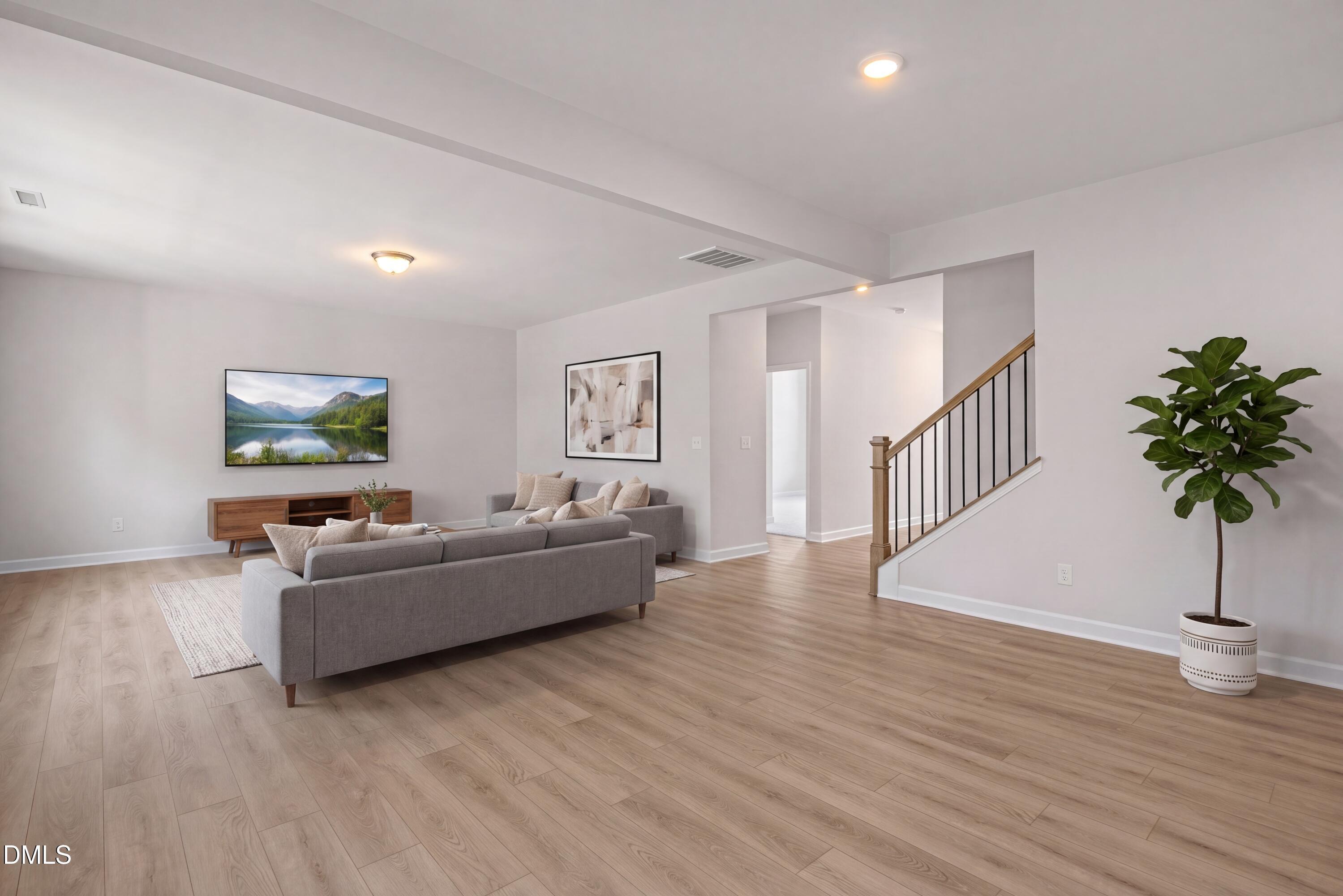 Spacious living room with light wood flooring and modern decor in The Hickory II B home in Lillington, North Carolina.