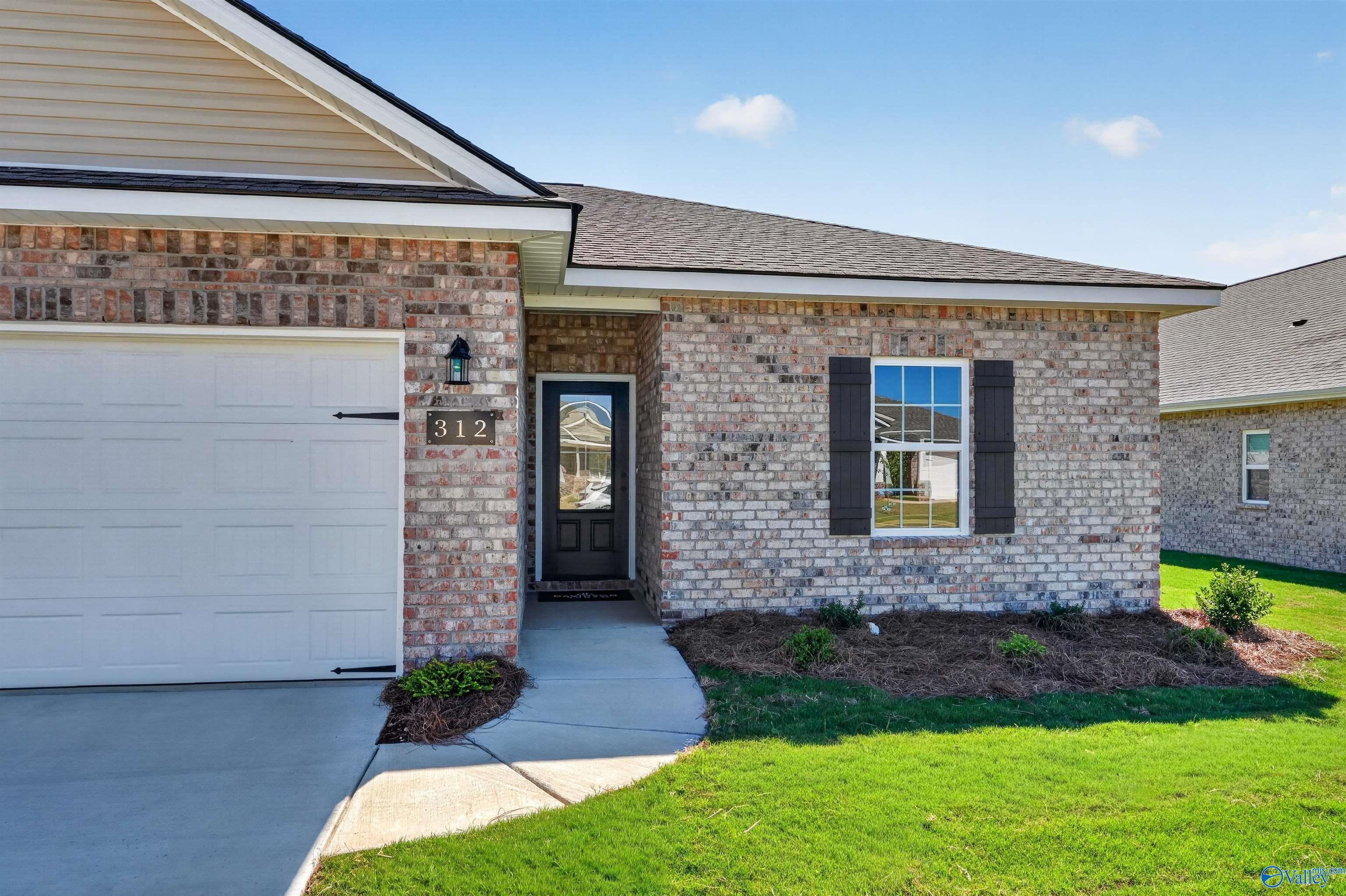 Brick front exterior with 2-car garage and landscaped yard at The Butler, a 3-bedroom Davidson Homes floor plan in Clearview, Hazel Green, Alabama