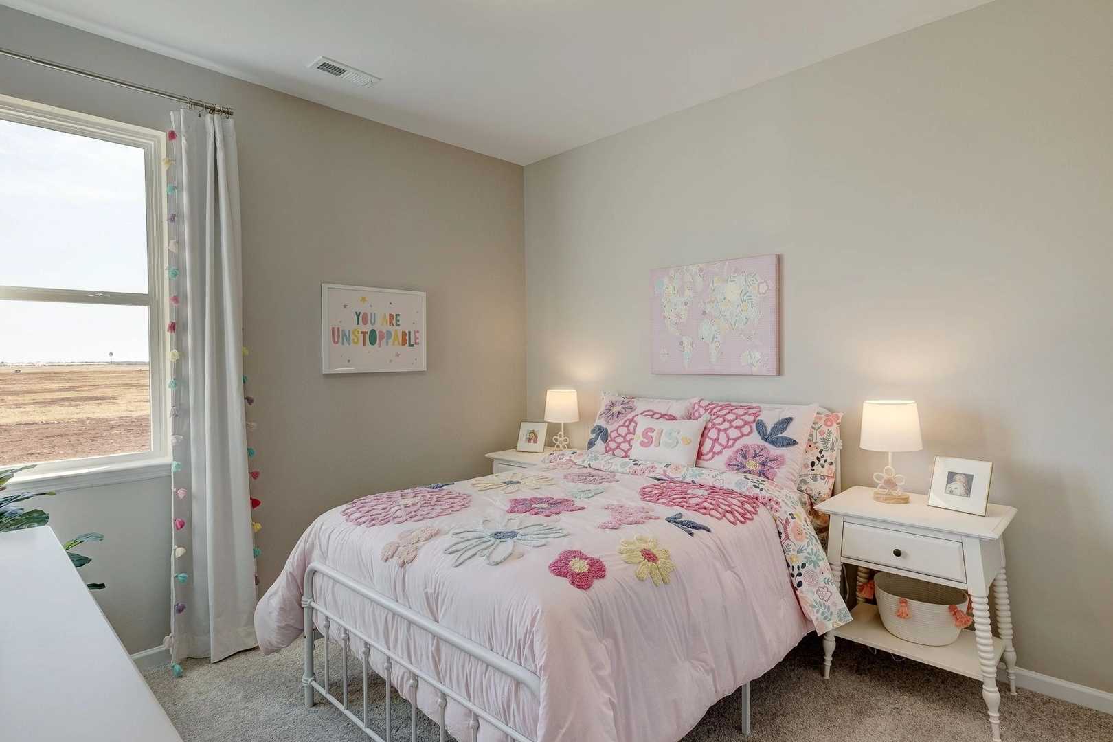 Charming girl's bedroom in Carroll Green Harvest AL with pink floral bedding, nightstands, and decorative wall art