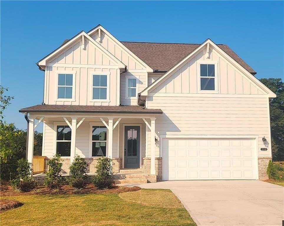 Modern 3-story white home with board-and-batten siding, covered front porch, 2-car garage in Wehunt Meadows, Hoschton, GA