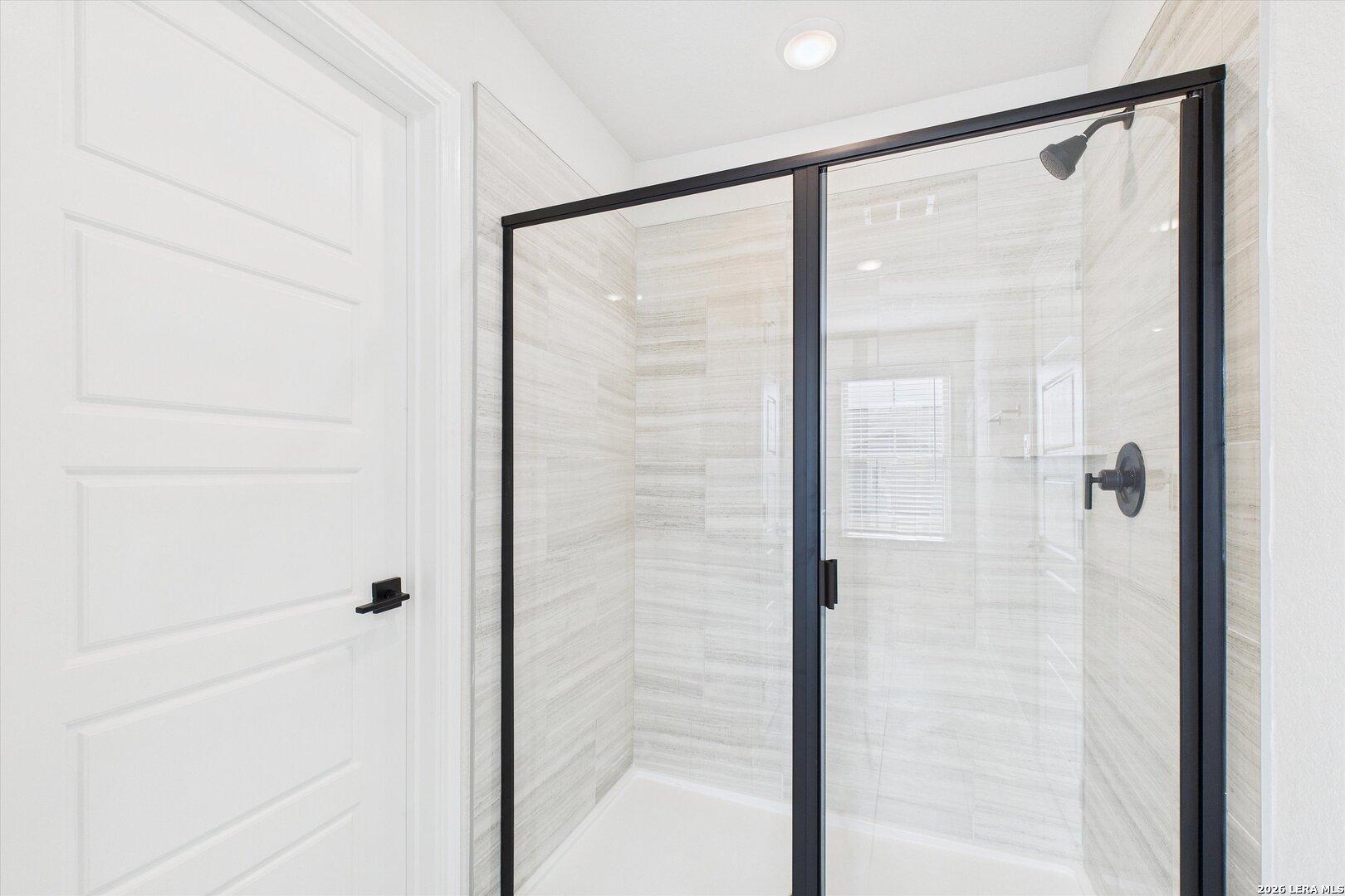 Modern walk-in shower with frameless glass enclosure, white subway tile, and rainfall head in The Gillian B master bath, Davidson Homes, San Antonio