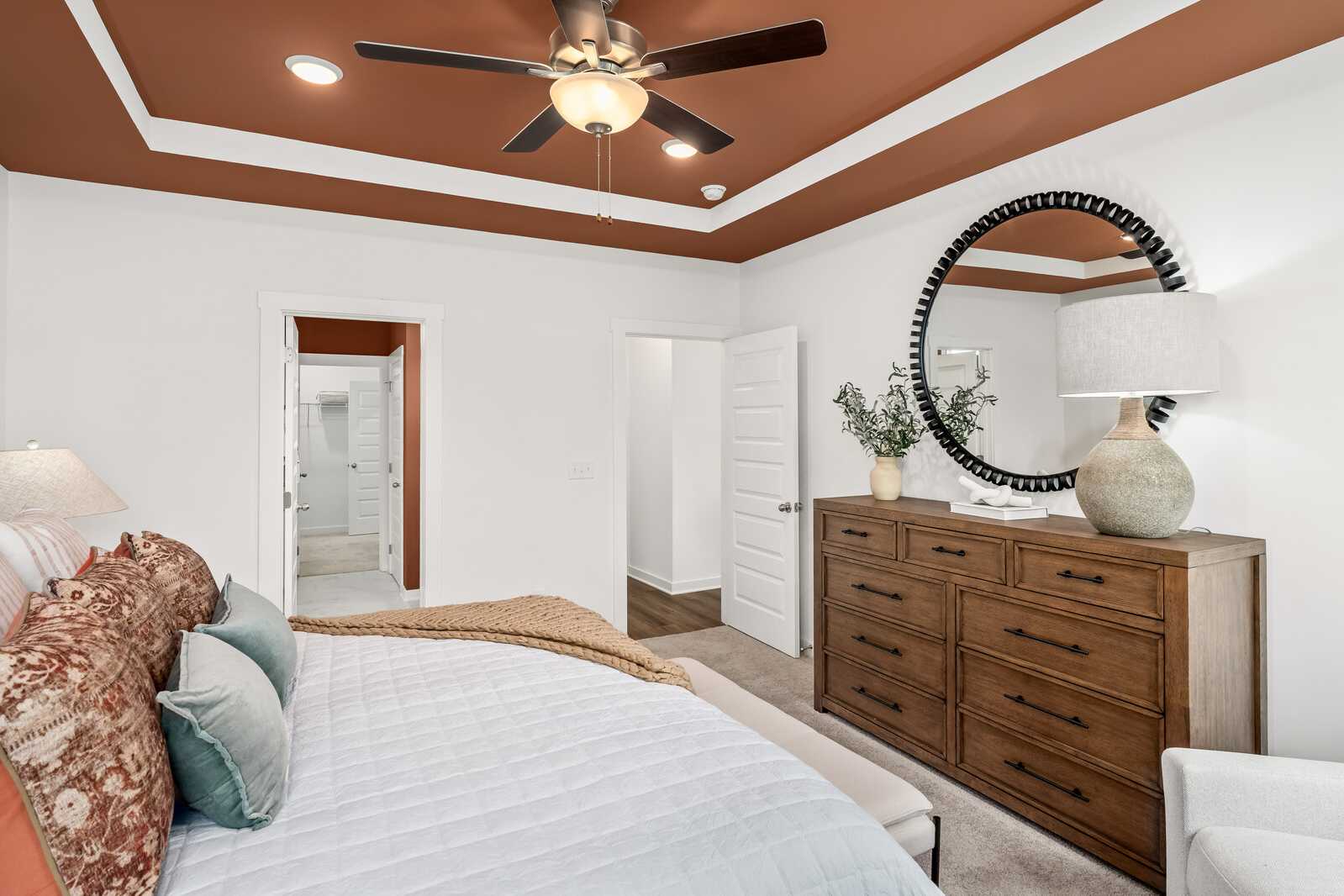 Spacious master bedroom at Calista Farms in White House TN with ceiling fan, king bed, wooden dresser and round mirror