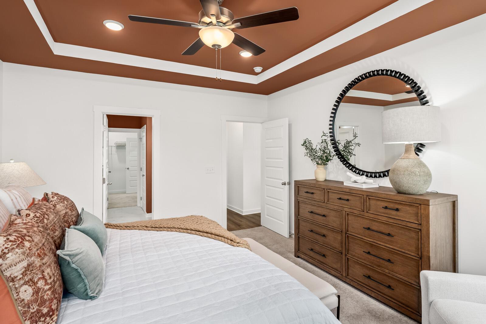 Spacious master bedroom at Calista Farms in White House TN with ceiling fan, king bed, wooden dresser and round mirror