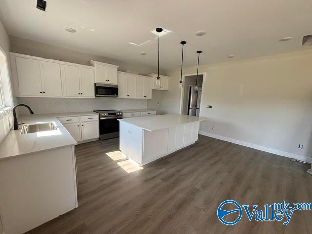 Modern kitchen with white cabinets, large island, and stainless steel appliances in The Chelsea B floor plan, Ramsay Cove.