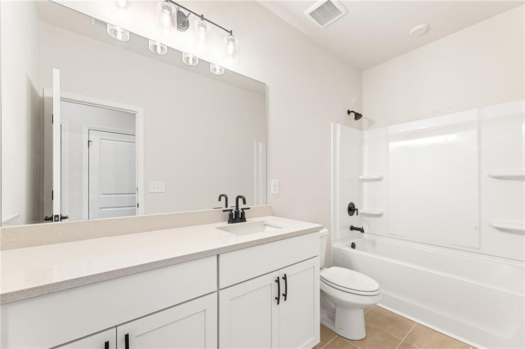 Bright master bathroom with white vanity, single sink, soaking tub-shower combo in Davidson Homes The Glenwood A, Loganville, GA