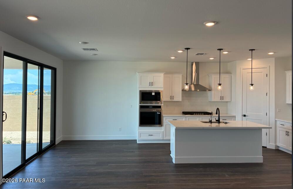 Modern white kitchen with island, stainless appliances, and sliding glass doors in Durango II G home, Prescott, Arizona.