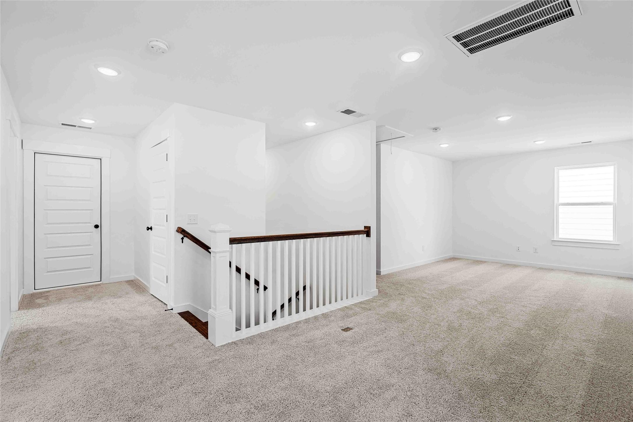 Spacious carpeted game room or loft area overlooking the staircase in a Davidson Homes The Ash O floor plan in Heartland.