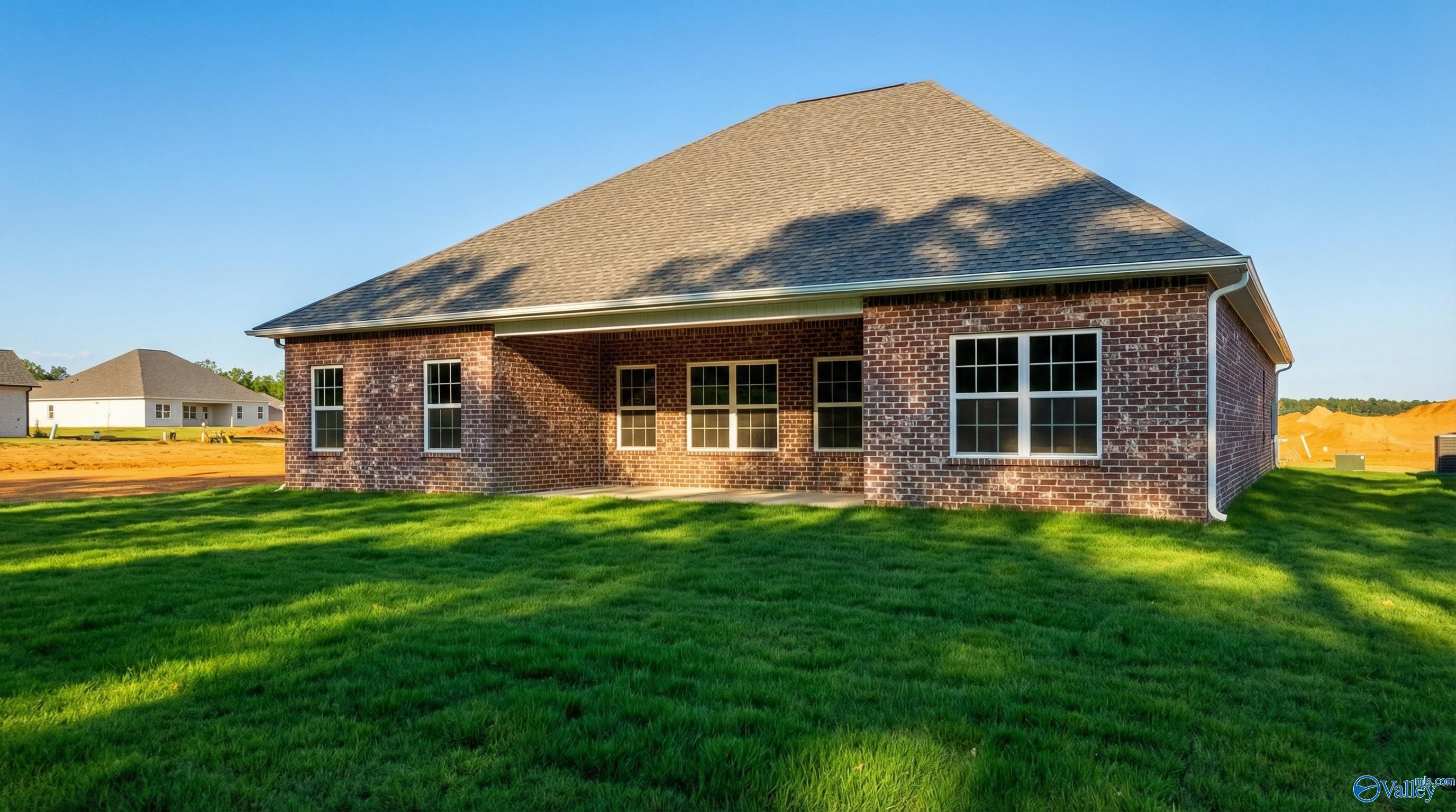 Brick back exterior of Davidson Homes The Rockford B with covered patio, large windows, and lush green yard in Cain Park, Hartselle, Alabama