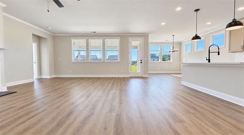 Bright open-concept living area with luxury vinyl plank flooring in Davidson Homes The Harrison H plan, Wehunt Meadows, Hoschton GA