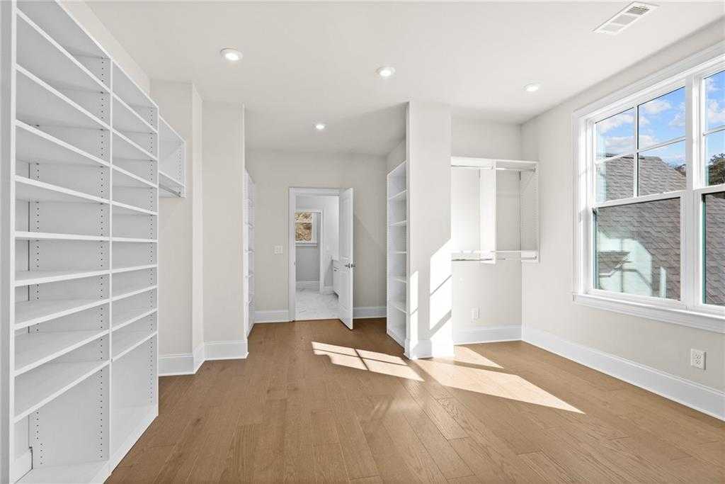 Spacious walk-in closet with white built-in shelving, hardwood floors, and natural light in Davidson Homes The Arlington A, East Cobb