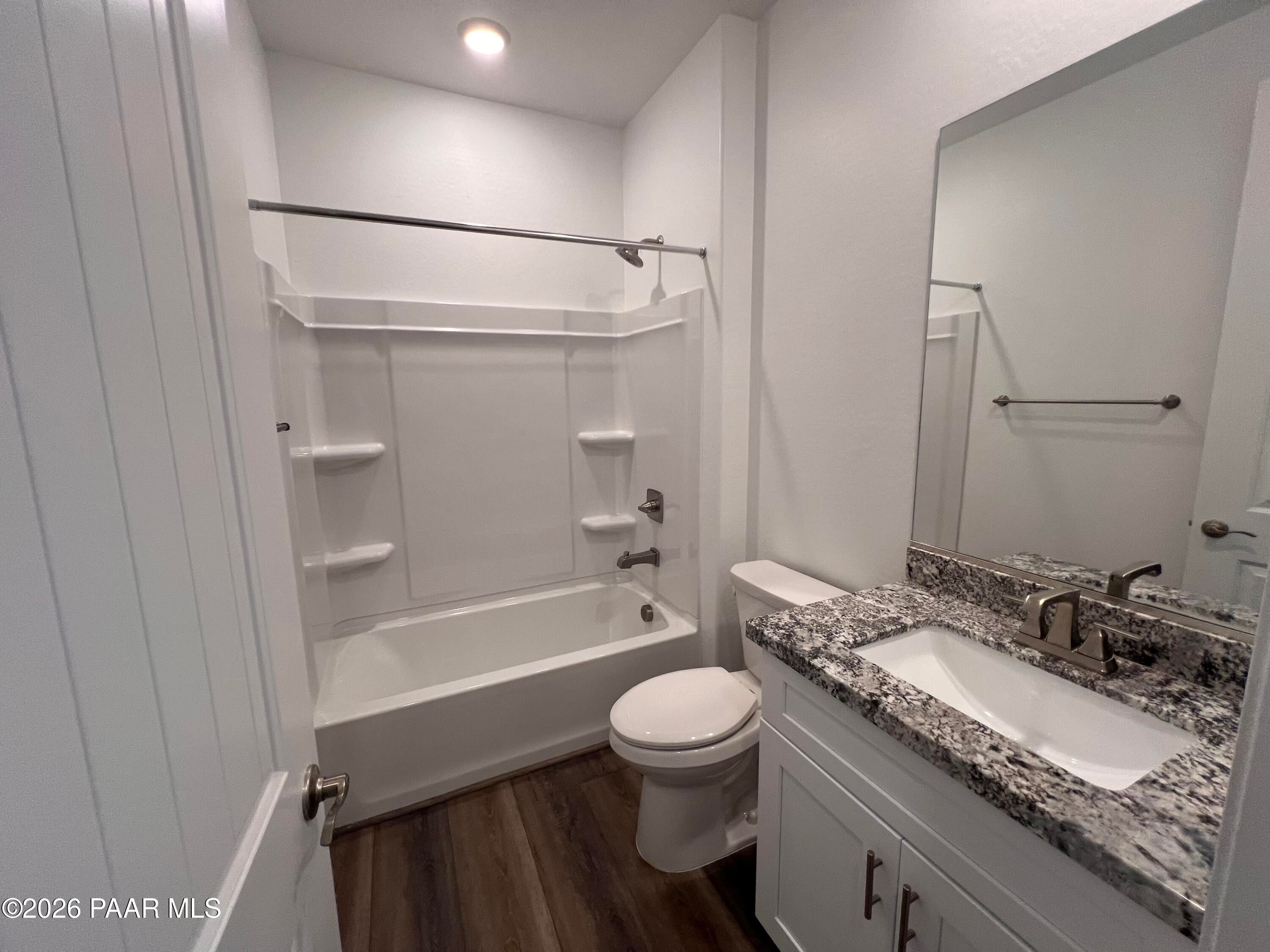 Modern guest bathroom with white tiled shower, deep soaking tub, granite vanity, and wood flooring in Davidson Homes Sunrise II A, Prescott AZ